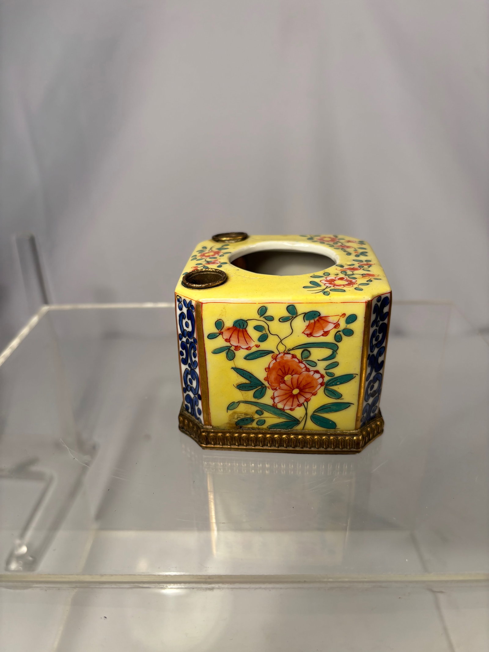 An European Enameled Porcelain Stand with Brass Mounts: A vintage European porcelain stand decorated with a yellow ground and hand-painted floral panels on each side. The top includes one larger central opening and two smaller side apertures, likely design