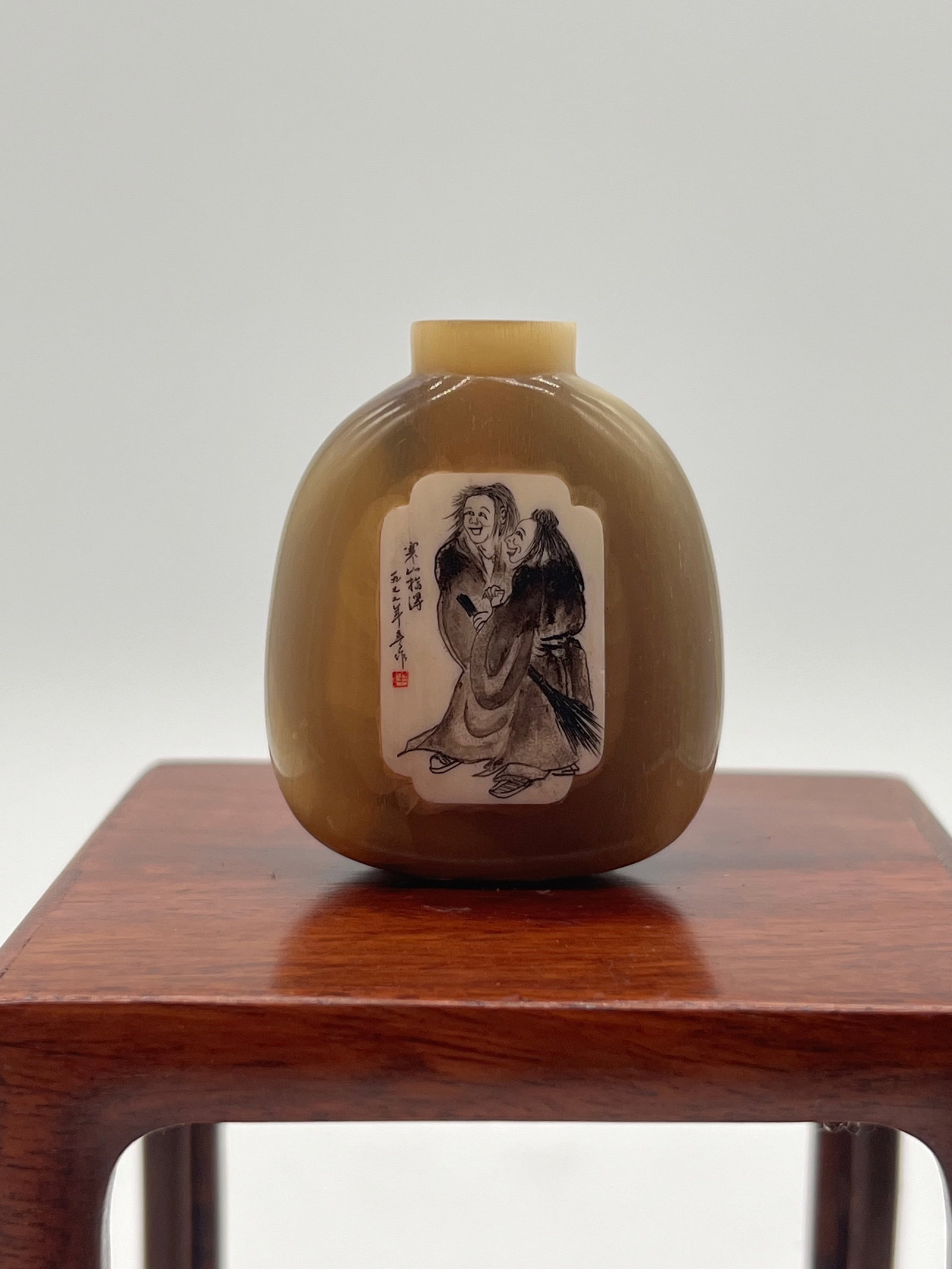 A Chinese Ox Horn Snuff Bottle: Qing Dynasty (1644-1912); blond Ox horn bottle with scrimshawed two bone inlaid panels with landscape to front and rear. Dimensions?Height: 5cm