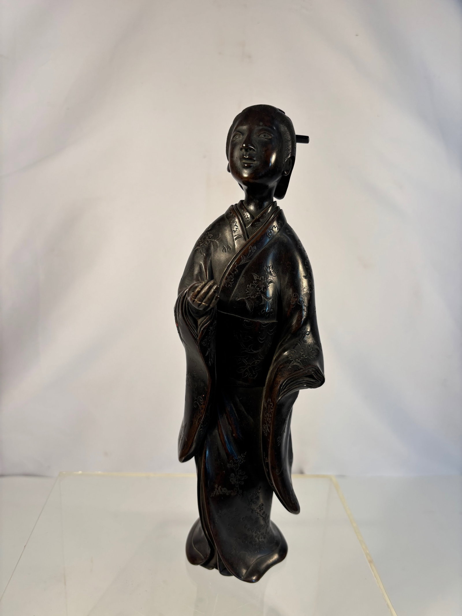 A Japanese-Style Bronze Figure of a Young Woman in Kimono, Meiji period: Meiji period (1868-1912); A fine Meiji period Japanese bronze figure depicting a young woman dressed in a traditional kimono, standing gracefully with her head slightly tilted and holding her garment 