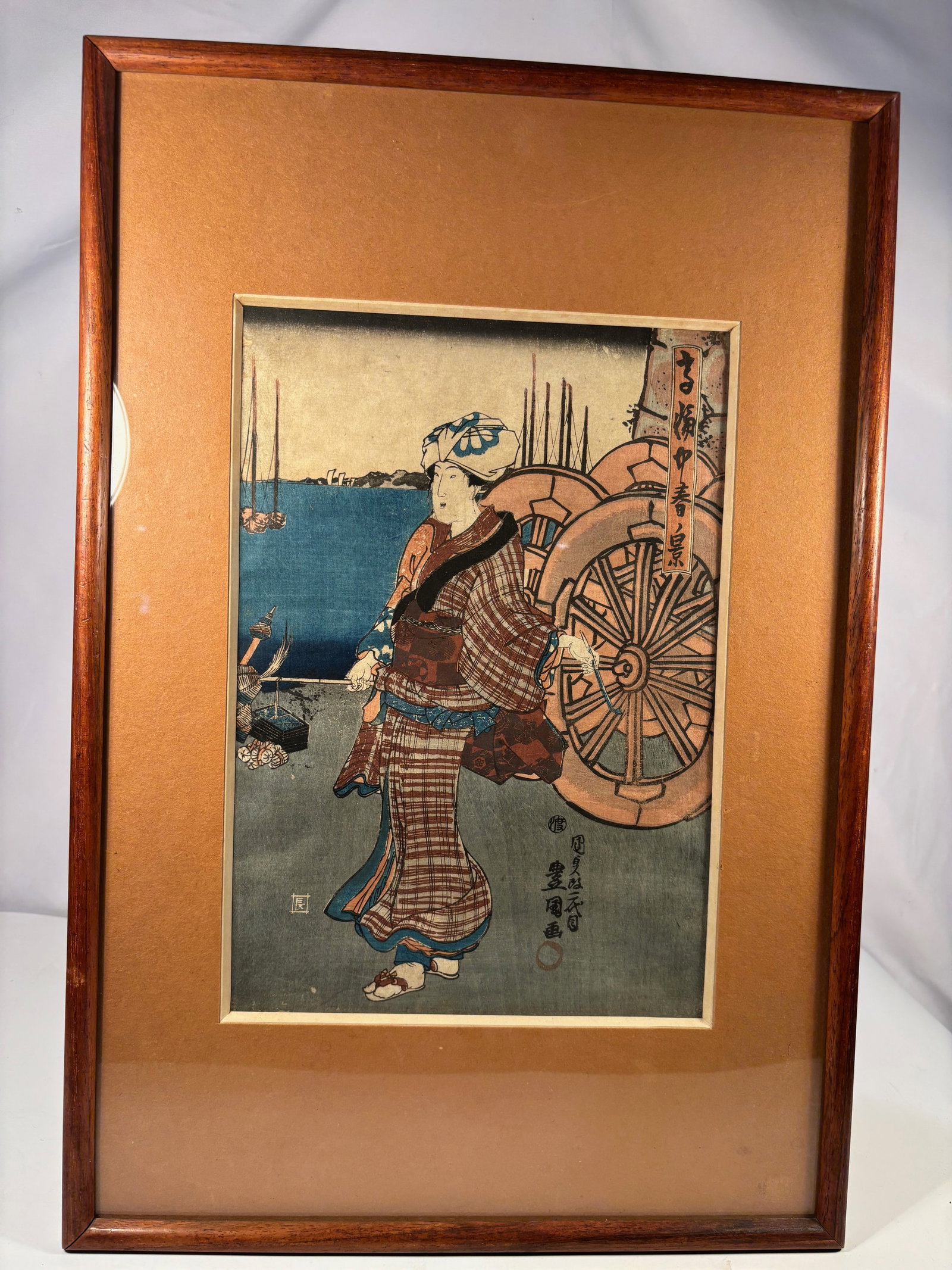 Utagawa Kunisada (Toyokuni III, 1786–1865) – “Spring Scene by the River,?? Edo Period: Japanese woodblock print depicting a standing bijin (elegant lady) beside ox-cart wheels with ships in the distance, symbolizing springtime by the water. Signed Toyokuni ga with publisher and censor s