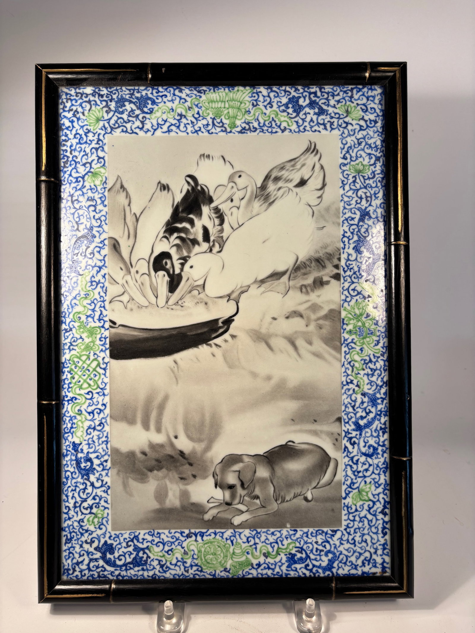 A Chinese Enamel Porcelain Plaque: Qing Dynasty (1644-1912); A finely painted Chinese porcelain plaque featuring a charming rural scene of ducks eating from a dish, with a dog resting nearby. Executed in detailed grisaille (black-and-w