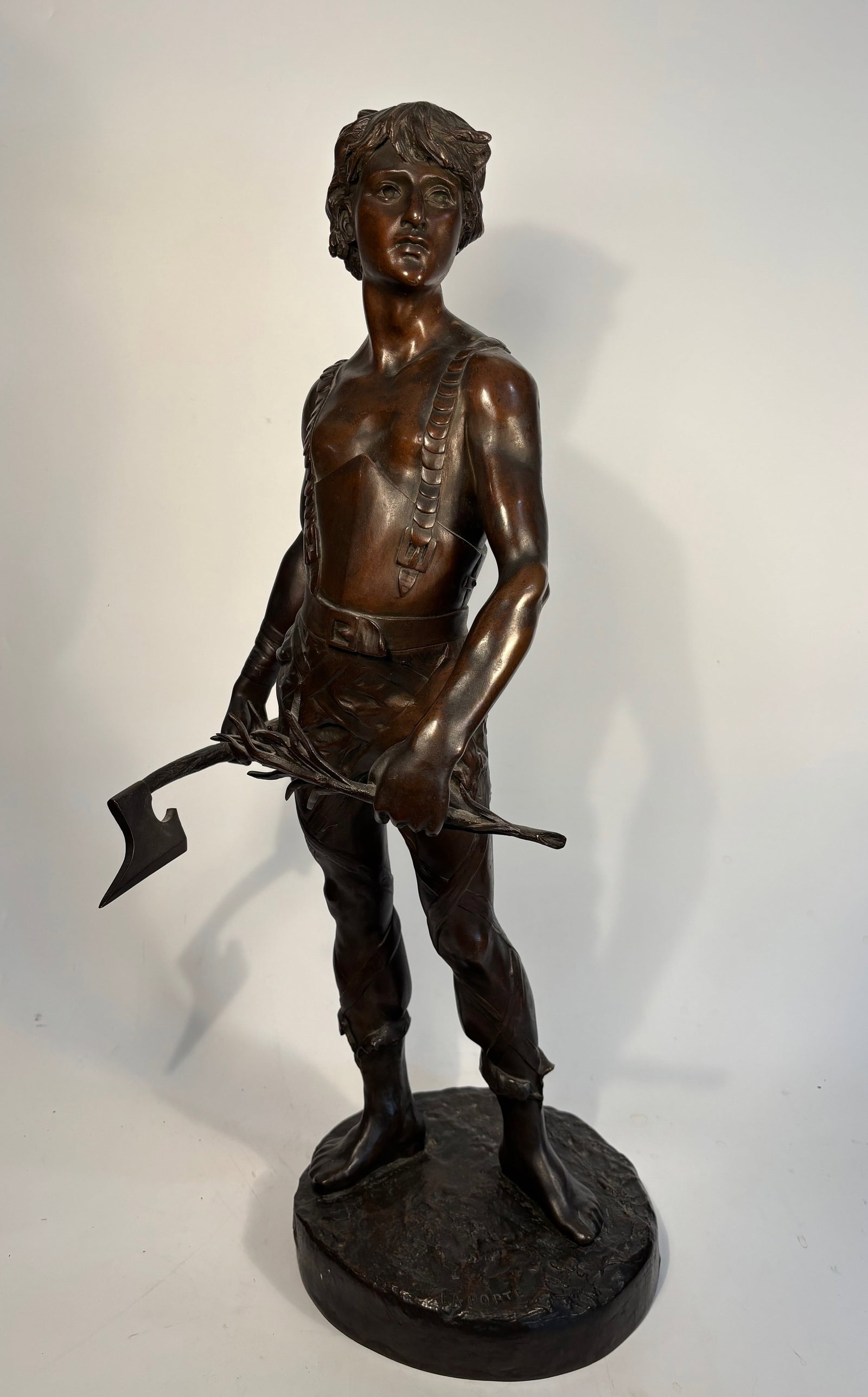 Émile Laporte (French, 1858–1907) Large Bronze Figure of a Youth with Axe, 26?? H: A finely cast and patinated bronze sculpture by Émile Laporte (French, 1858–1907), depicting a young man standing in a naturalistic pose, bare-chested and holding an axe by his side. The figure sta