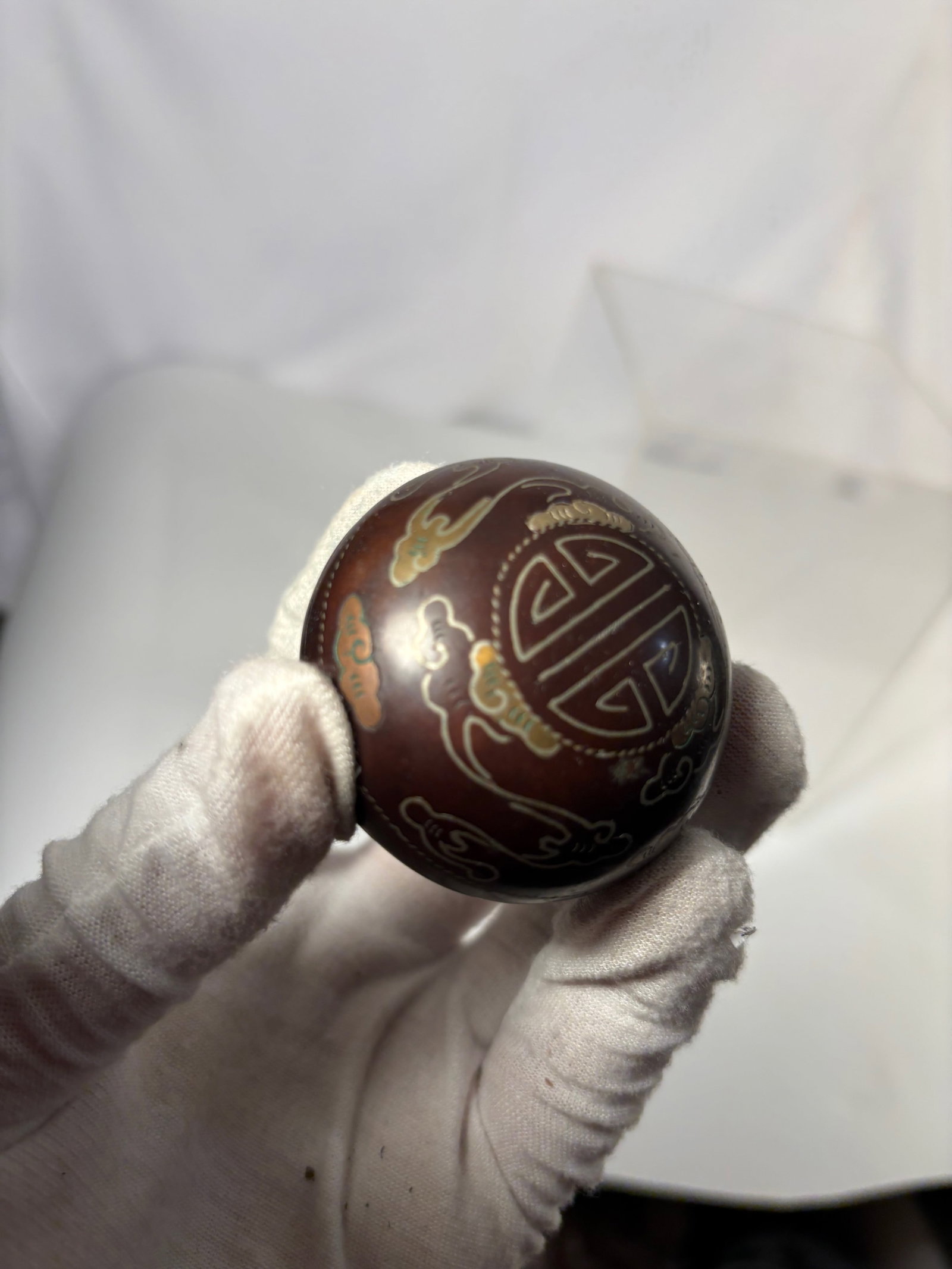 A Chinese Silver Inlaid Metal Longevity Motif Covered Box: Chinese small metal box of rounded form, decorated with silver inlaid longevity character and cloud motifs. The domed cover and body are finely ornamented with stylized patterns in contrasting metal. 