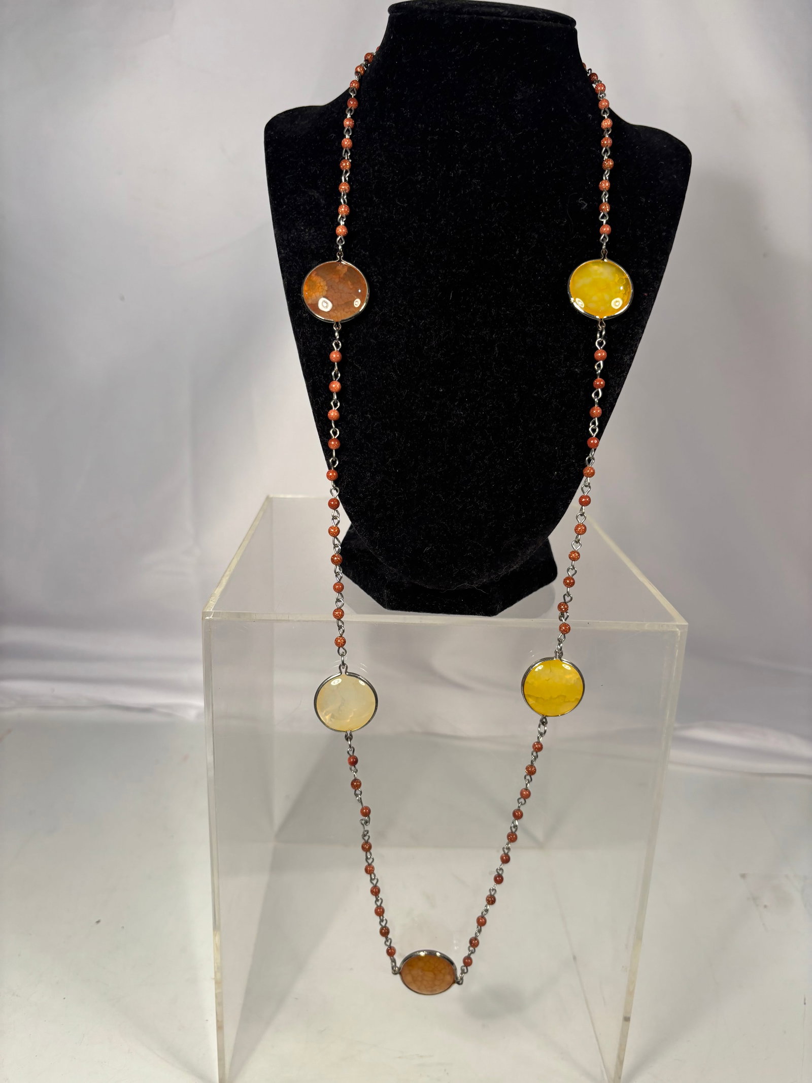 Multi-Stone Agate and Chalcedony Necklace: Decorative necklace featuring bezel-set oval cabochons in shades of honey yellow, amber, cream, and brown, linked by strands of small coral-colored beads and metal chain. The semi-translucent stones d