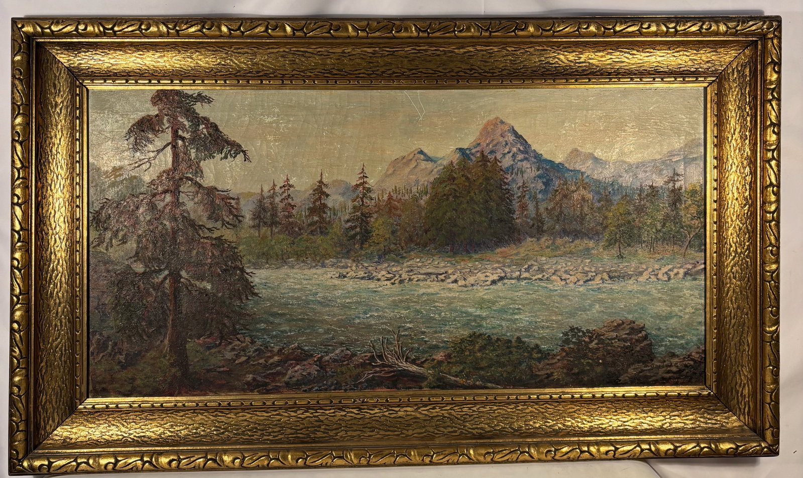 A Large European Mountain Landscape Oil Painting, Signed M. Goodman 1959: Oil on canvas depicting a mountain landscape with river and pine trees. Signed lower right “M. Goodman.” Executed in textured impasto brushwork. Housed in an ornate gilt frame. Likely mid-20th
