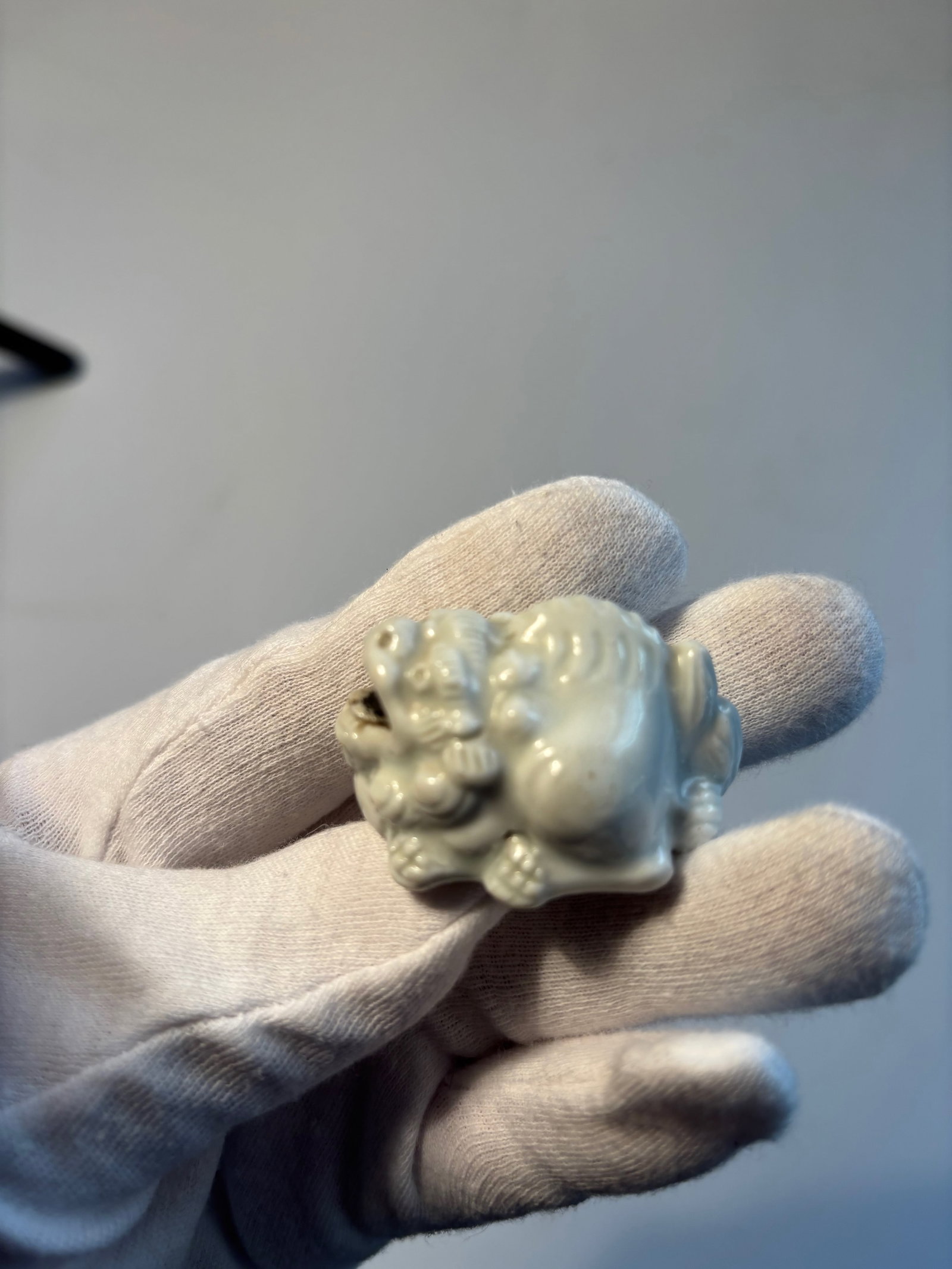 A Hirado porcelain netsuke of a shishi: 19th century; The white-glazed pottery lion dog seated, facing ahead, its head raised and its open mouth containing a loose ball, unsigned.The property of a Private Collector. Dimensions? 4.2cm (1 5/8