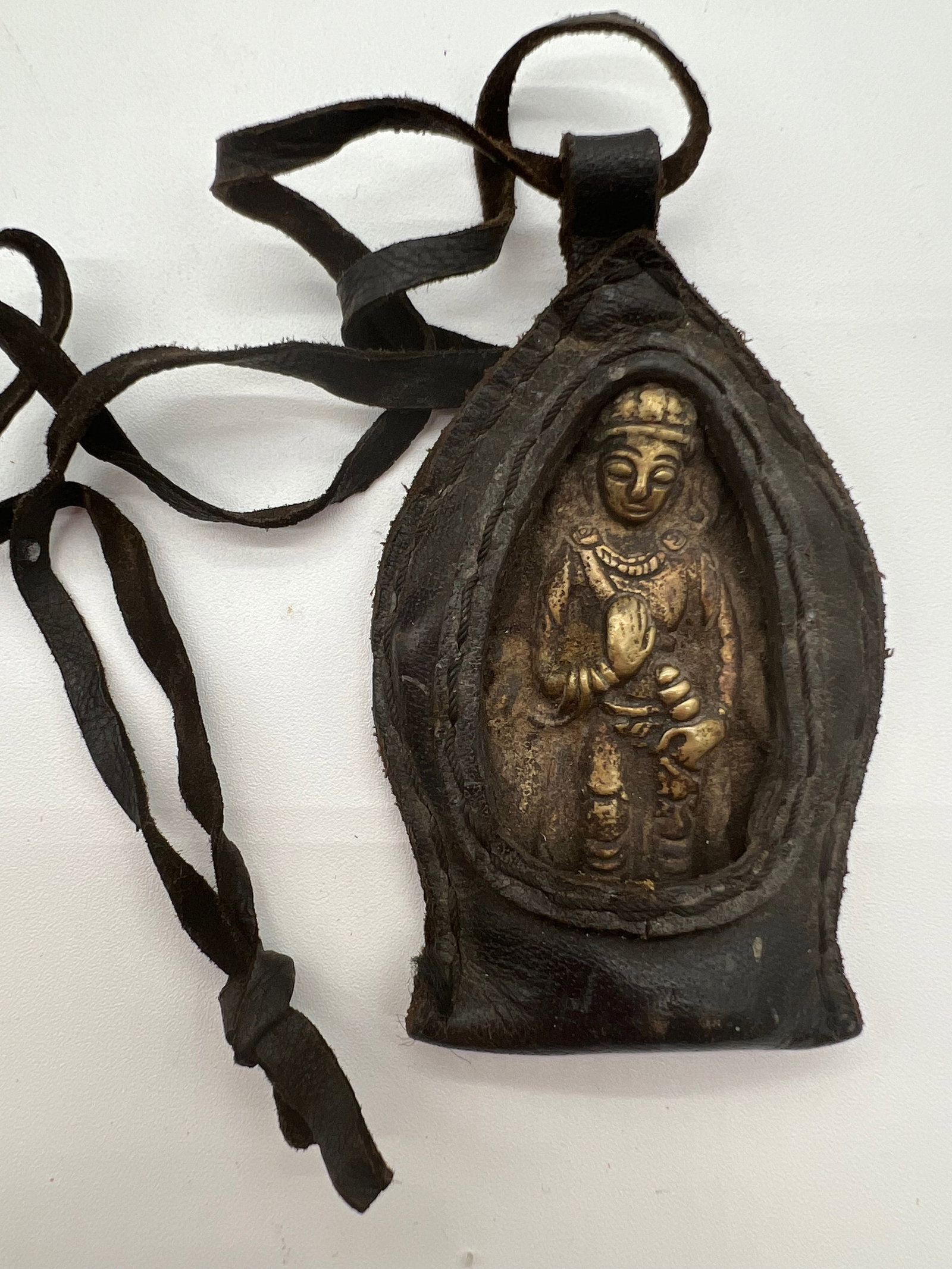 A portable Tibetan bronze Buddhist in amulet case: 19th century; The central figure seems to be made of metal, possibly bronze . The leather casing or pouch surrounding the figure serves to protect it during travel, emphasizing the portable and person