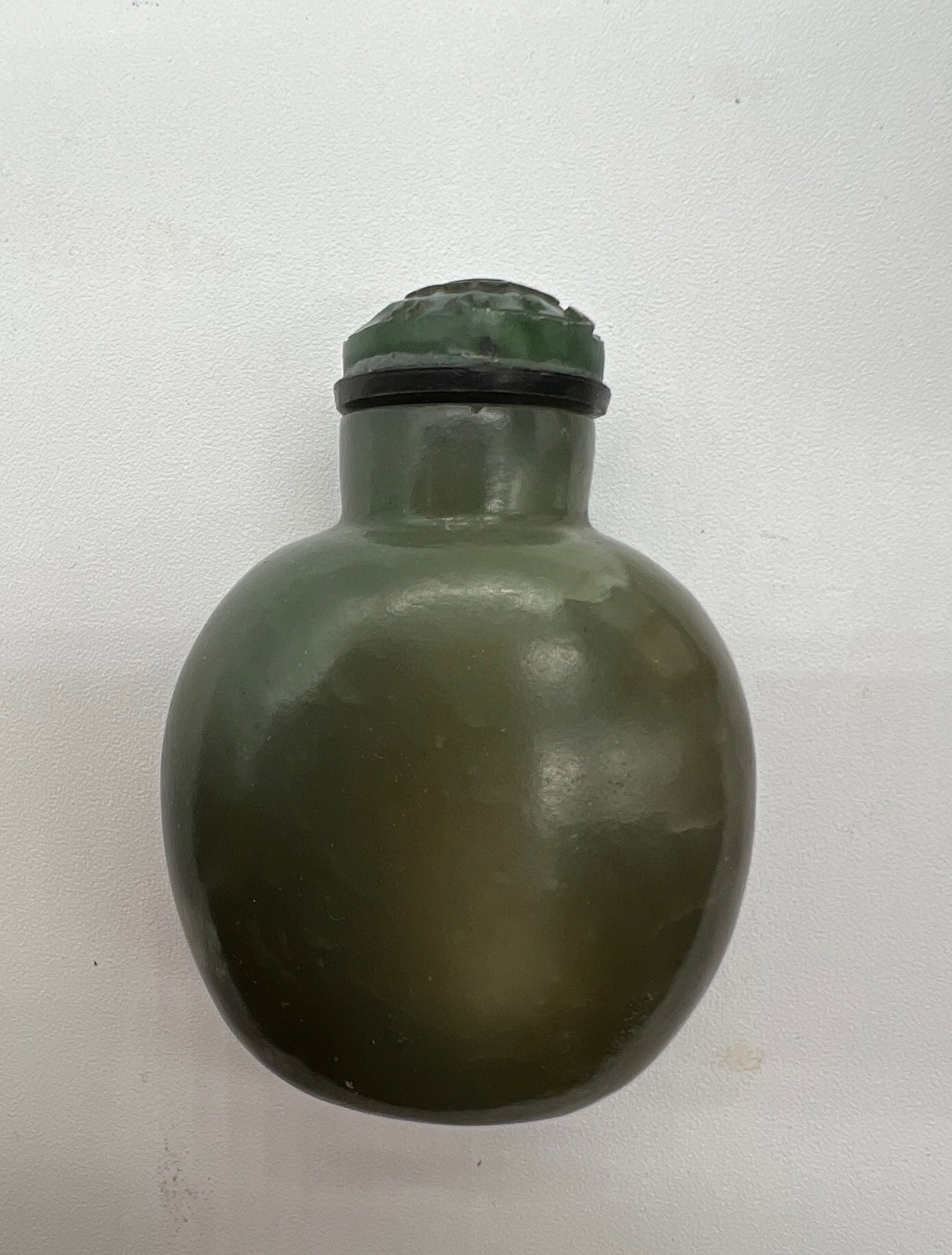 A Chinese green jade snuff bottle with carved top: Qing Dynasty (1644-1912); The bottle’s design is simple yet elegant, highlighting the natural beauty of the stone without excessive decoration. Dimensions?Height: 6cm