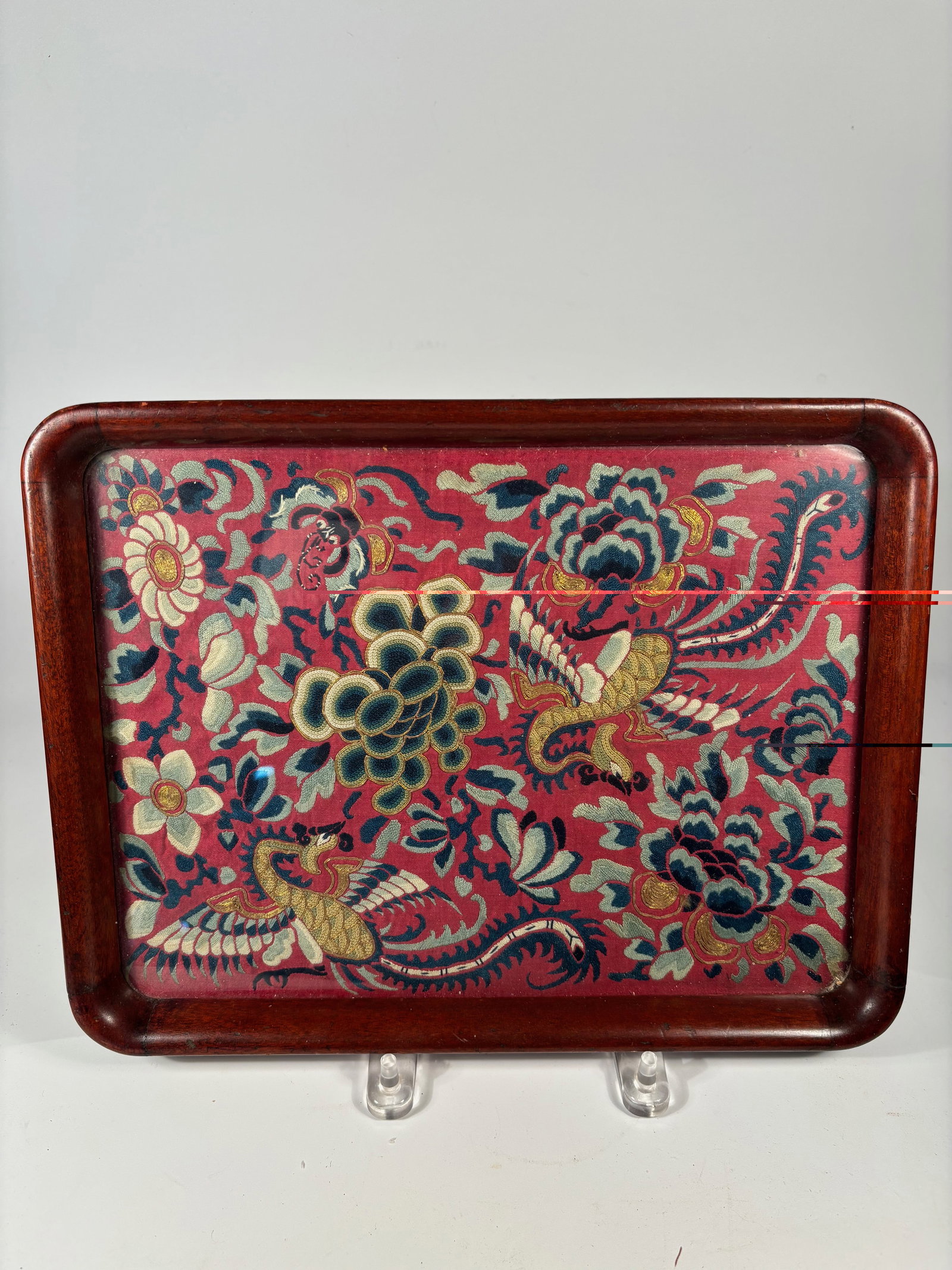 A Fine Chinese Silk Embroidery Fragment with Phoenix and Floral Motifs: Qing Dynasty(1644-1912); A rectangular Chinese lacquered wood tray featuring a vivid hand-embroidered silk panel inset to the base. The embroidery is finely worked with colorful silk and couched gold-