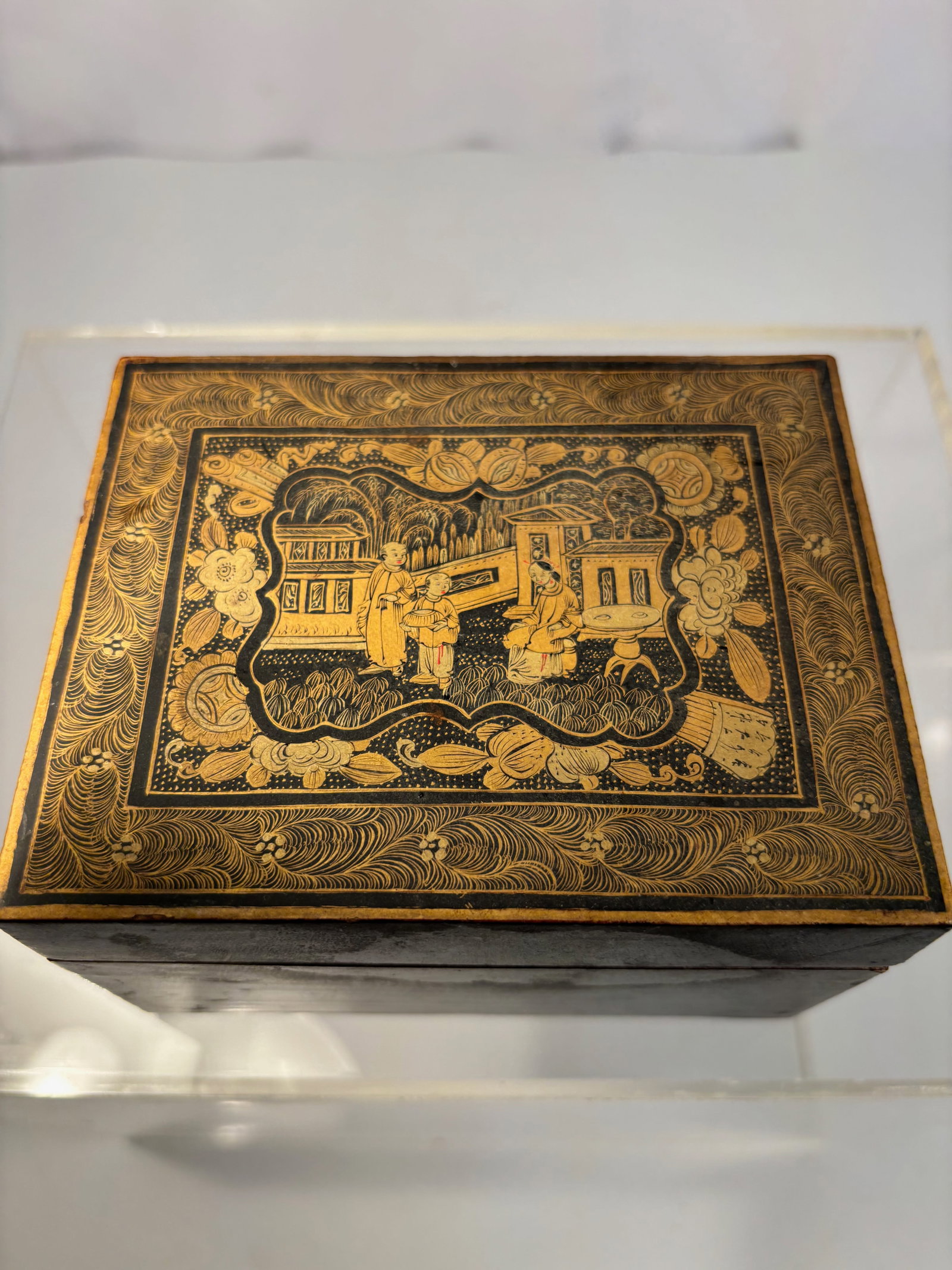 A Chinese Export Gilt Lacquer Box, Canton, Qing dynasty(1644-1912): Of rectangular form, the lid richly decorated in raised gilt lacquer with a domestic garden scene, depicting court ladies and attendants in a pavilion landscape, surrounded by a border of scrolling fo
