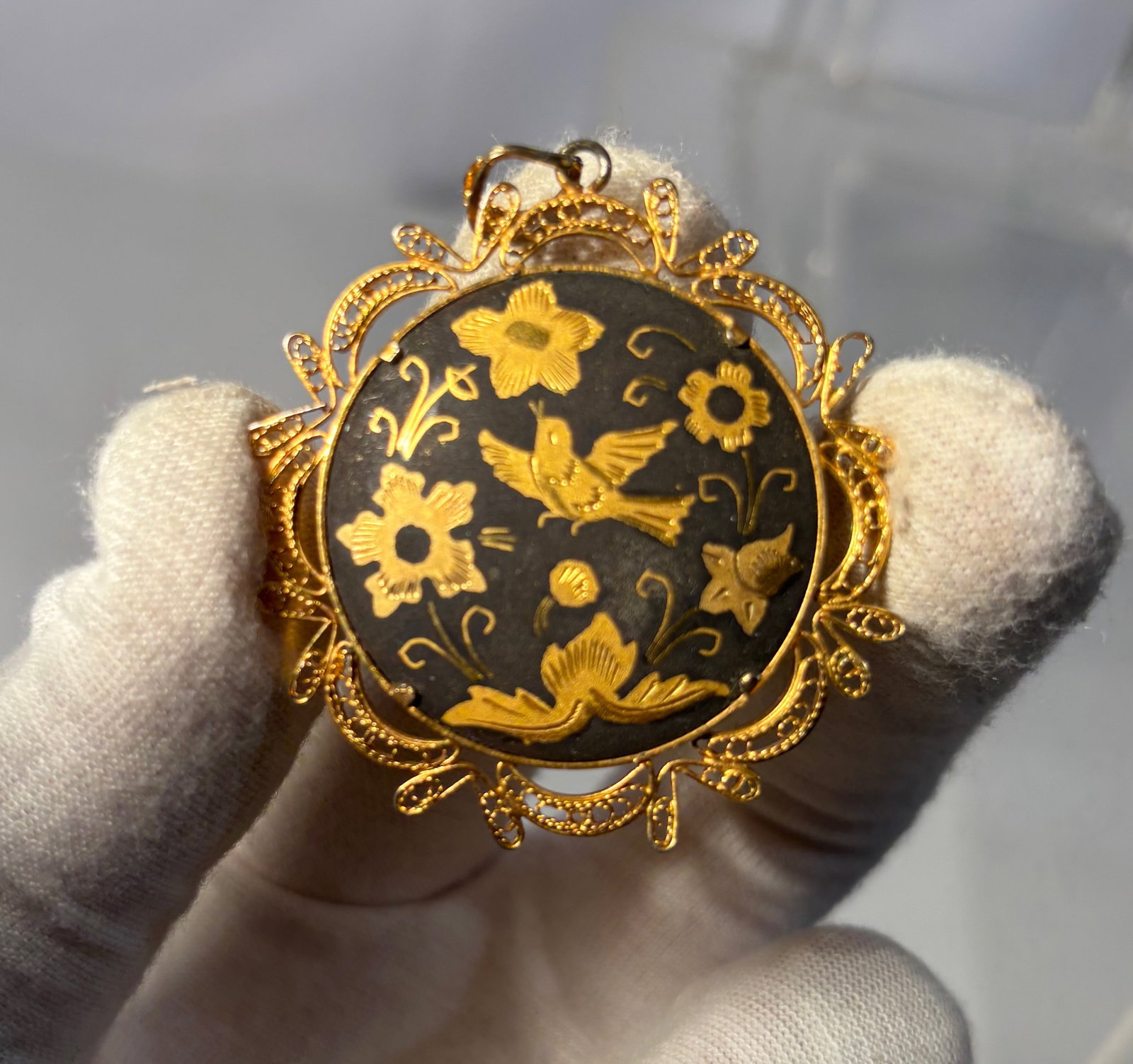 A Victorian Gilt Niello Pendant with Bird and Floral Motif, Late 19th Century: Late 19th century Victorian niello pendant, featuring a circular black ground finely engraved and decorated with gilt bird and floral motifs. The central plaque depicts a bird in flight surrounded by 