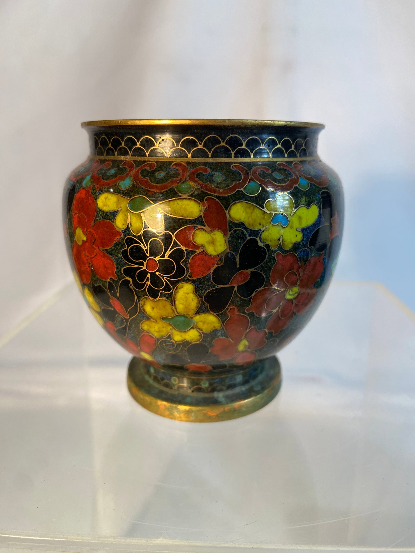 Chinese Cloisonné Enamel Floral Vase: Chinese cloisonné enamel vase of rounded form, decorated with dense floral and scrolling foliate motifs in red, yellow, green, turquoise, and black enamels against a dark ground. The vessel with gilt