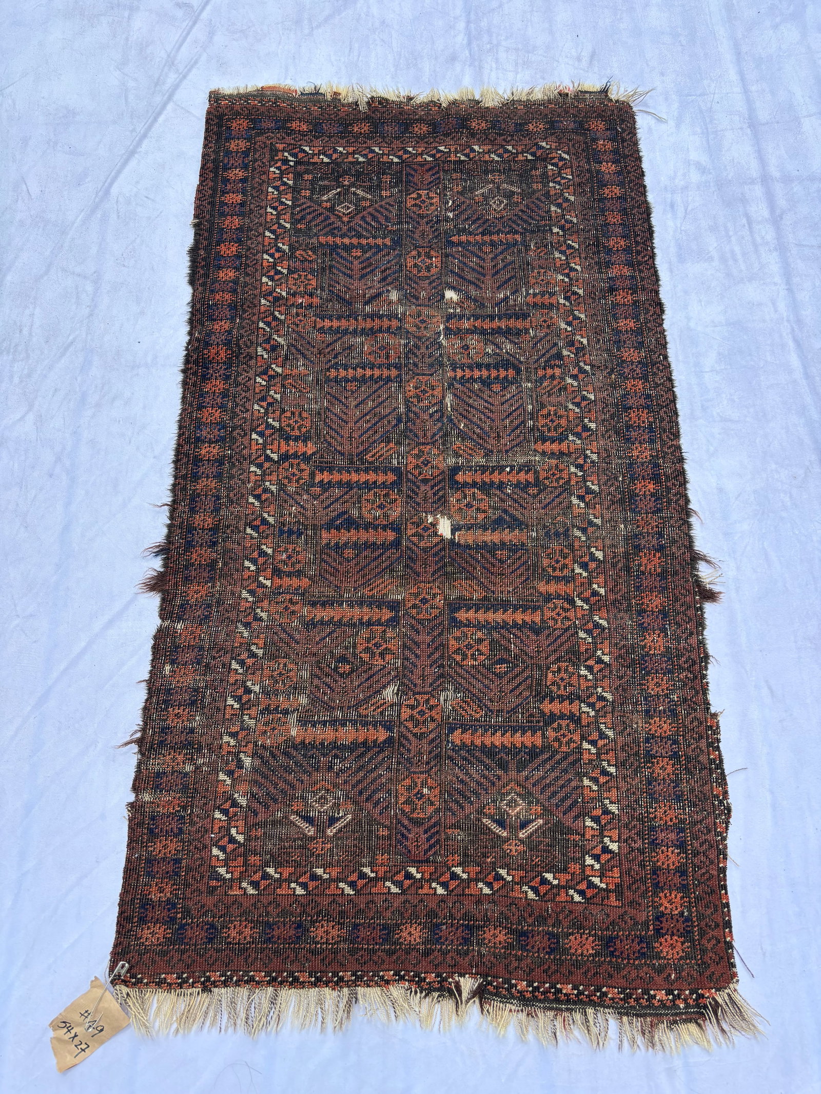 Antique Baluch / Belouch Tribal Rug 54 x 27 in.: Hand-knotted Baluch tribal rug featuring repeating geometric compartment motifs in deep brown, rust, and indigo tones. The field displays traditional arrow and latch-hook inspired elements with narrow