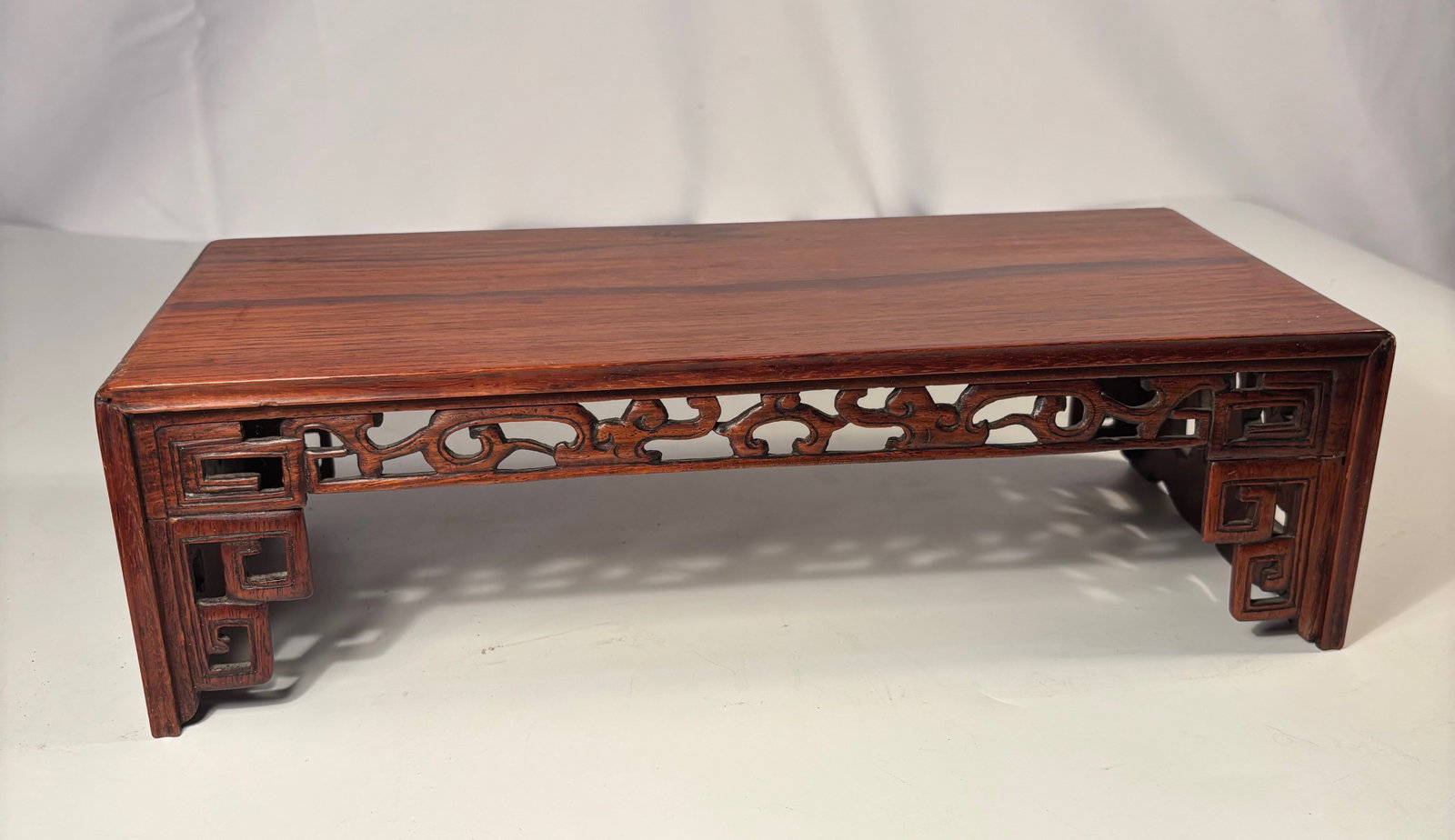 A Fine Chinese Huanghuali Rectangular Display Table with Openwork Apron: Qing dynasty(1644-1912); The table is of elegant proportion, constructed with a single well-figured panel top set within a rectangular frame. The aprons are finely carved in openwork with ruyi-scroll 