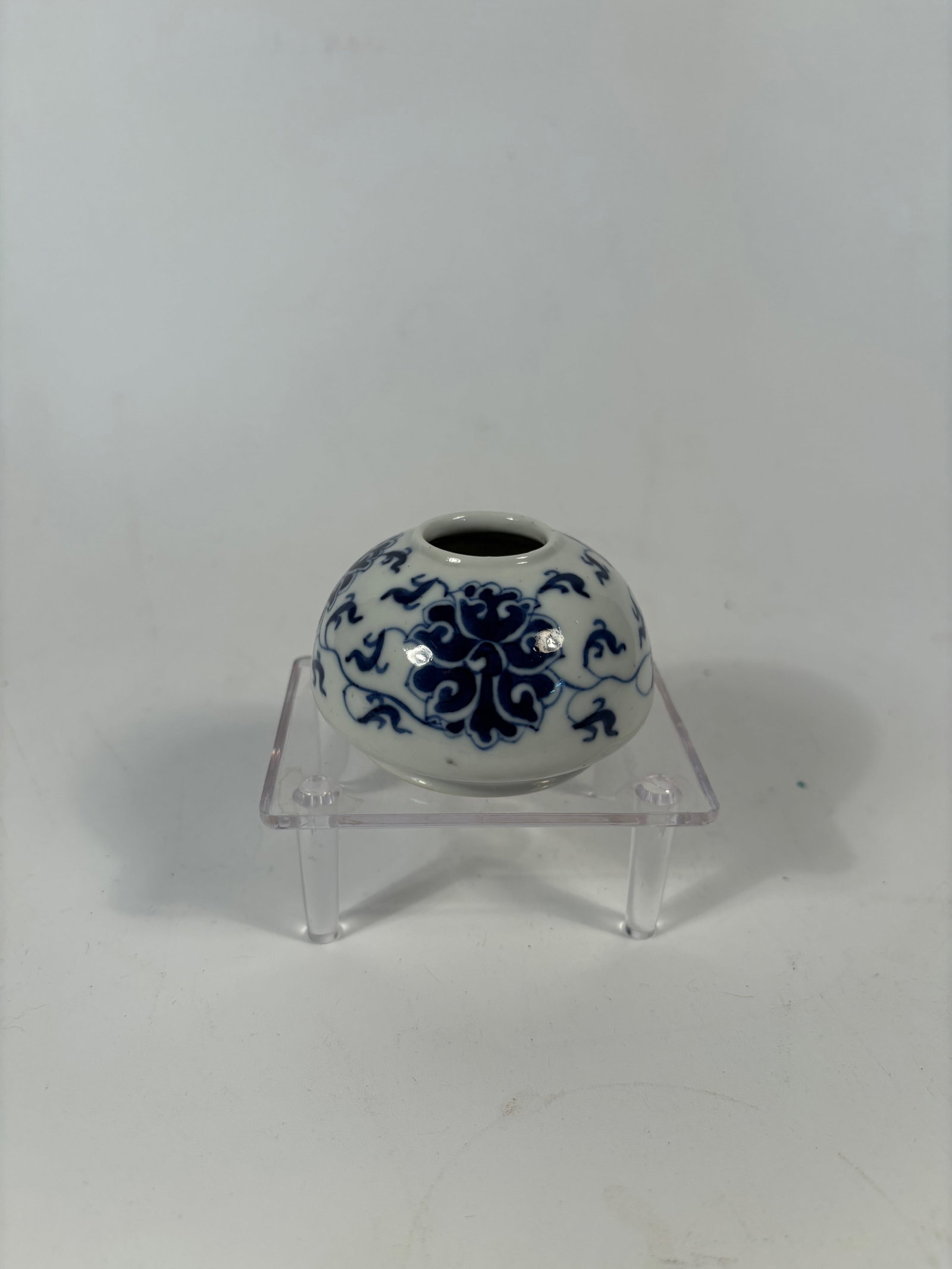 A Chinese blue and white porcelain water pot: Qing dynasty(1644-1912);Of globular form with a short neck and wide mouth, the body is decorated in underglaze cobalt blue with lotus blossoms and scrolling foliage in a continuous frieze. The glaze i