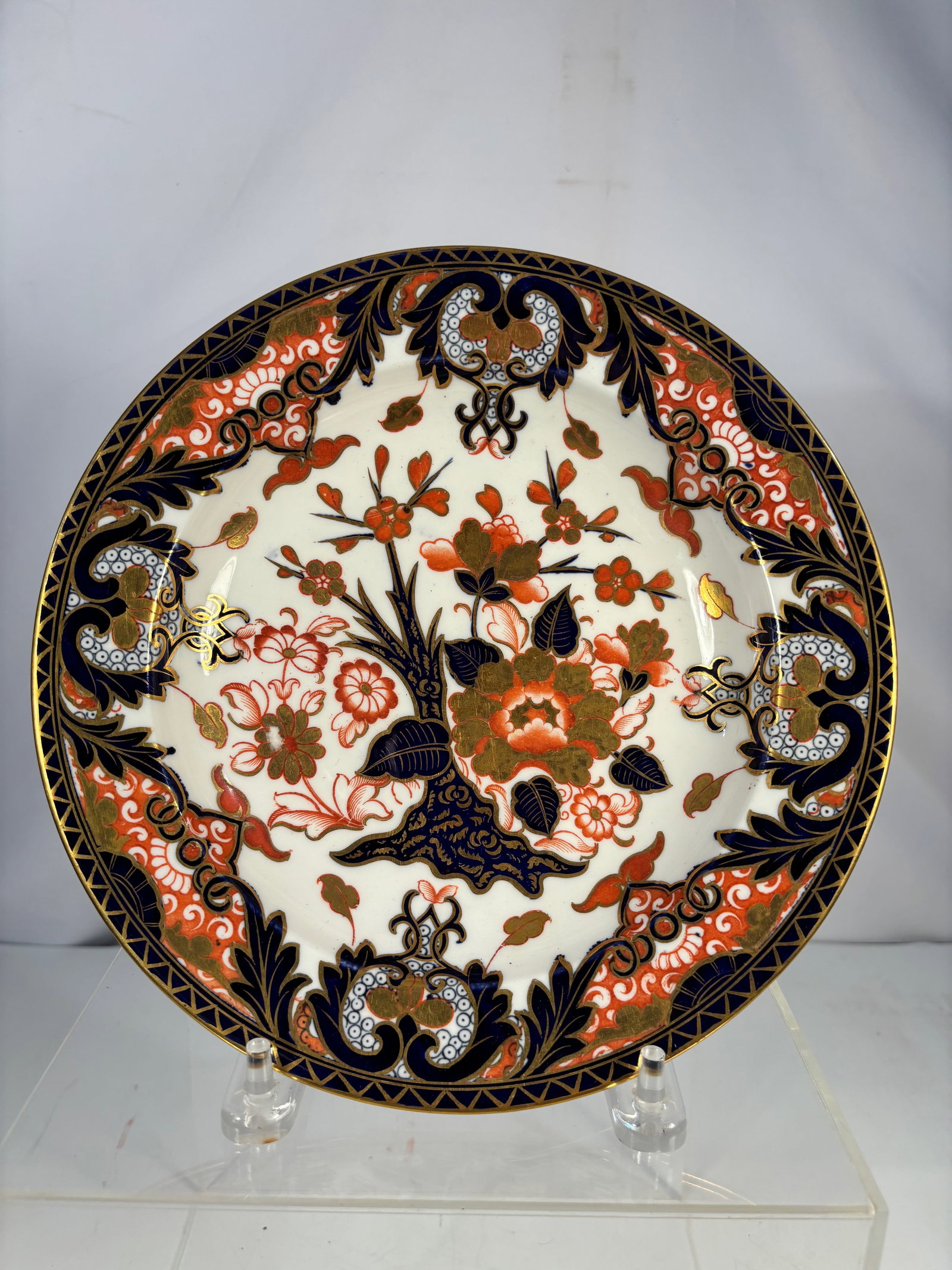 An English Derby Porcelain Imari-Palette Plate, Late 18th Century: English Derby porcelain plate, late 18th century, decorated in a rich Imari palette of iron red, cobalt blue, and gilt. The plate features a central floral spray surrounded by stylized foliate and orn
