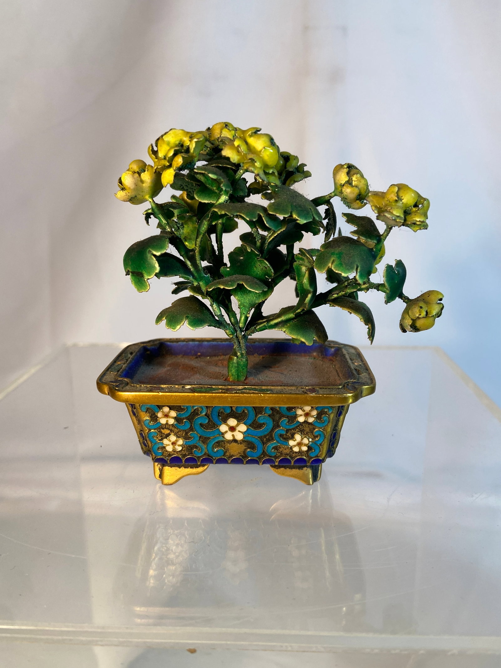Chinese Cloisonné Miniature Bonsai Flower Arrangement: Chinese cloisonné enamel miniature bonsai-style flower arrangement featuring painted metal blossoms and foliage rising from a rectangular cloisonné jardiniere decorated with scrolling foliate motifs