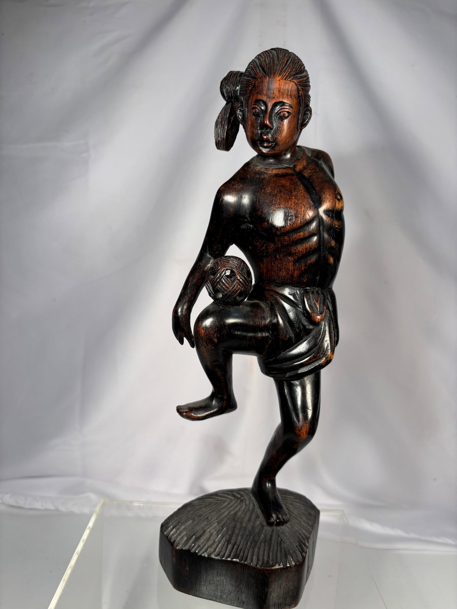 Vintage Hand-Carved South Asian Hardwood Tribal Figure Sculpture: Vintage hand-carved hardwood tribal figure sculpture, likely originating from Indonesia or the Philippines. The sculpture depicts a stylized male figure in a dynamic balancing pose while holding a car