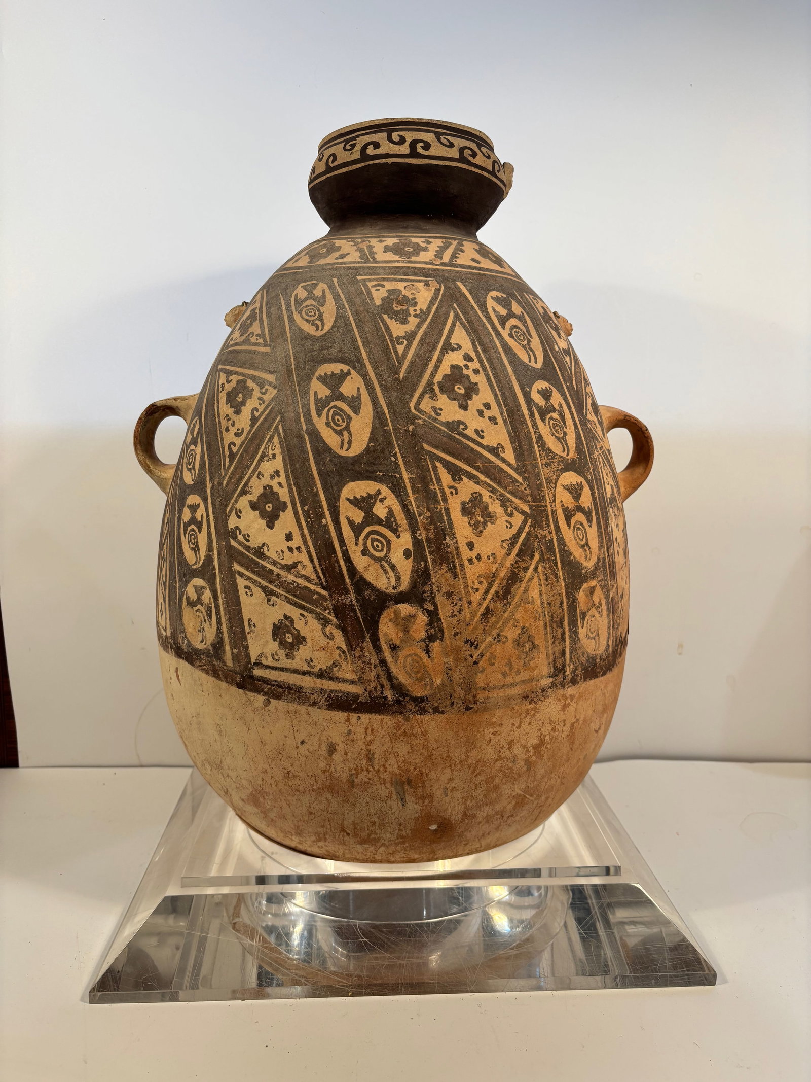 Terracotta Vessel with Geometric Motifs: Chancay, ca.1000-1470 CE. The black geometric designs on a cream slip, the loop handles, and the chalky earthenware body. Dimensions?Height: 20 inches. Width: 15 inches. Base included.