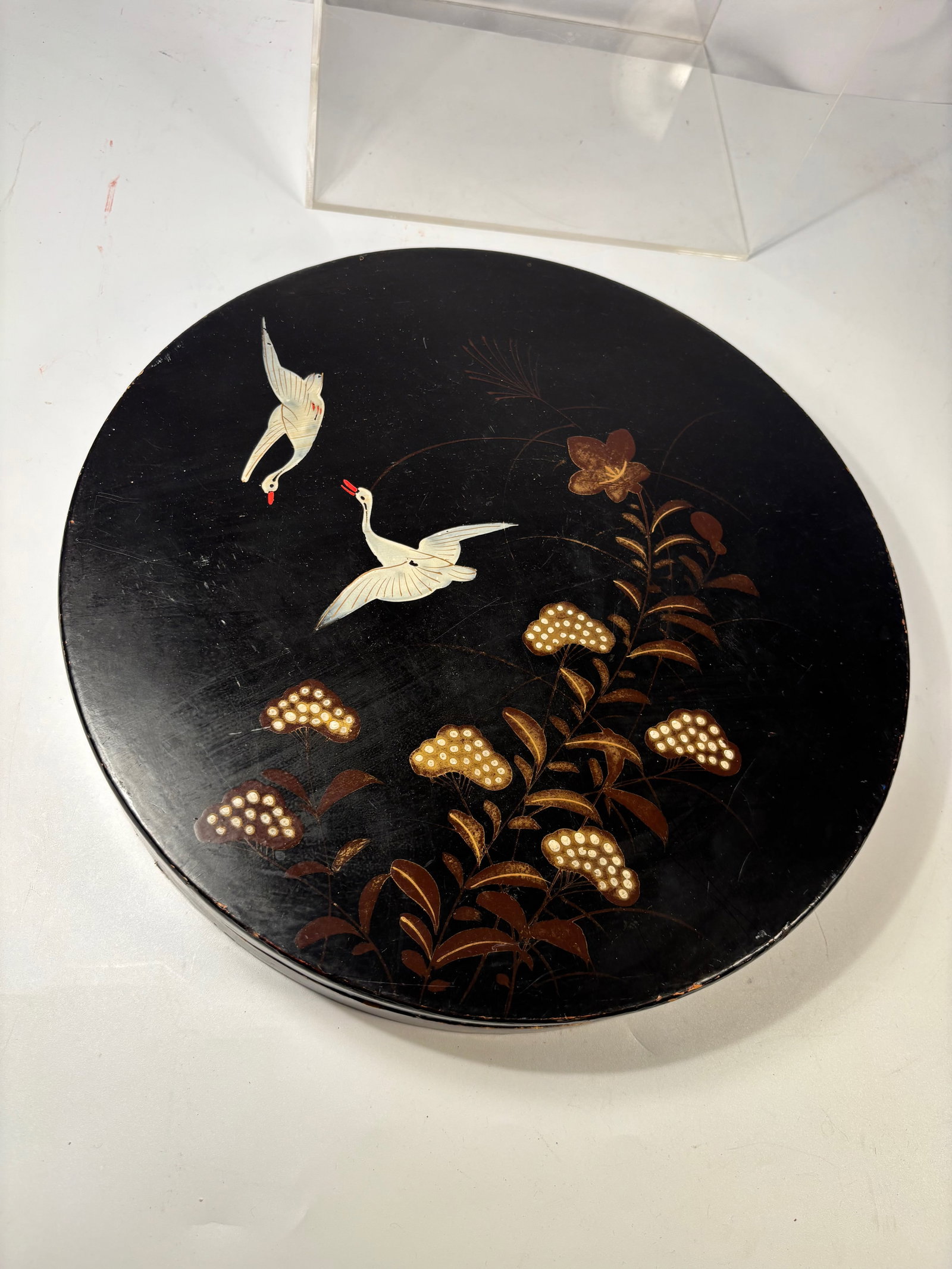 Japanese Black Lacquer Box with Crane Decoration, Made in Japan: Japanese black lacquer circular box, decorated with cranes in flight above stylized floral and foliage motifs rendered in gilt and polychrome lacquer. The composition features two white cranes with re