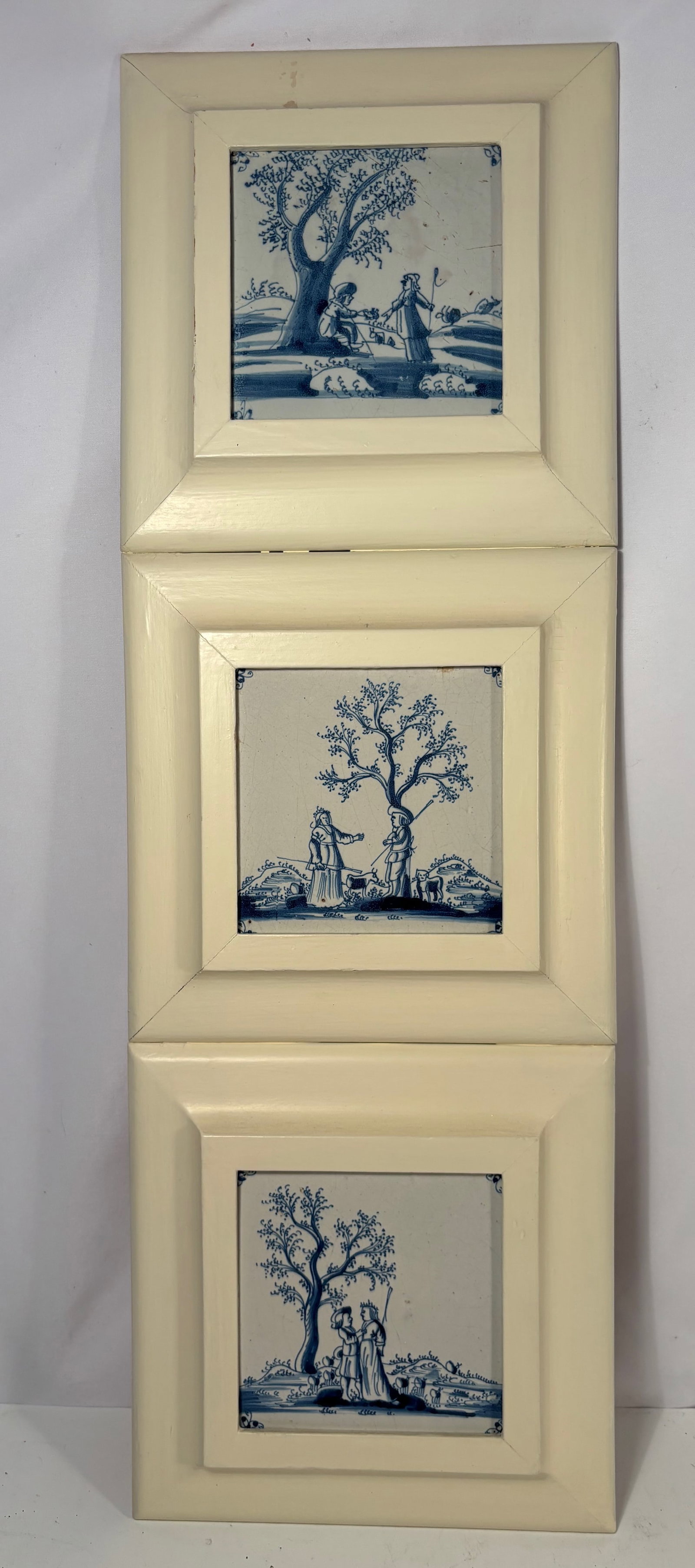 Set of Three Antique Dutch Delft Blue and White Tiles with Pastoral Scenes, 18th century: A set of three antique Dutch Delft blue and white ceramic tiles depicting pastoral scenes including figures fishing, shepherds, and a fountain. Each tile decorated with traditional corner motifs and p