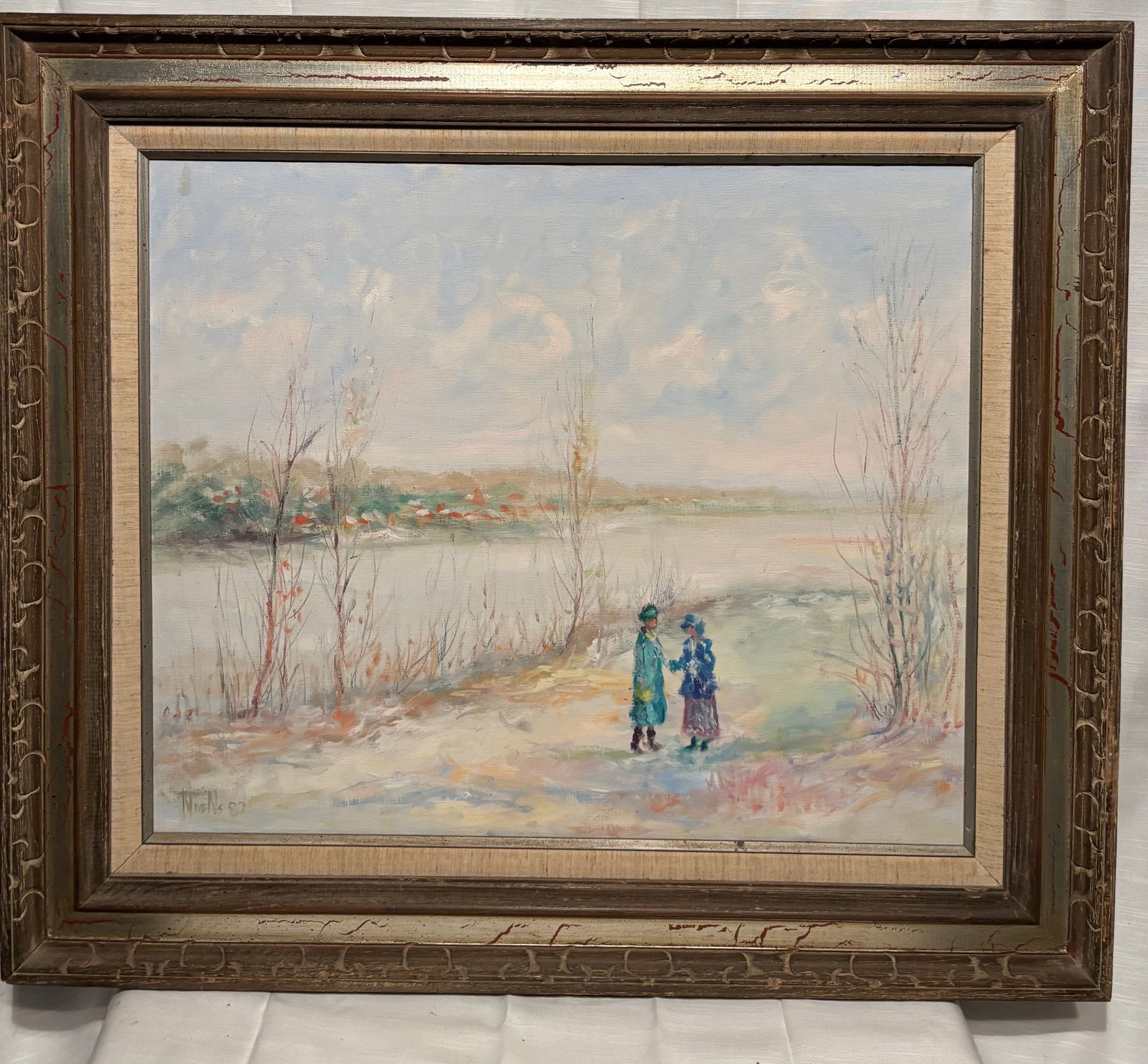 Signed Nivens Riverside Landscape with Figures, 1982: A serene impressionist-style riverside landscape painting signed Nivens and dated 1982. The composition depicts two elegantly dressed figures standing along a quiet shoreline, with delicate winter tre