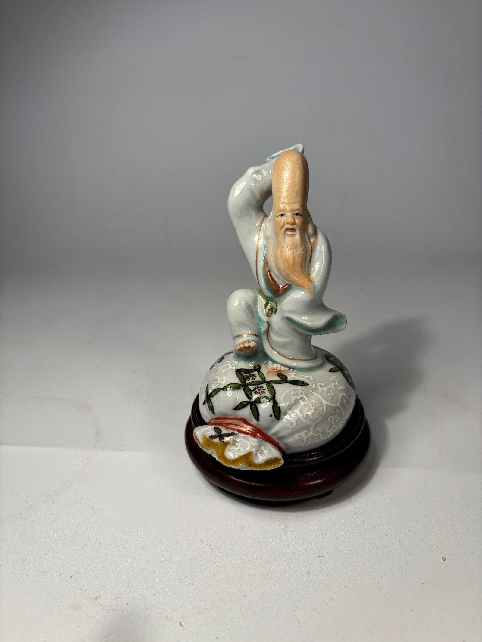 A Japanese porcelain FUKUROKUJU GOD KUTANI statue: Early 20th Century; A finely glazed porcelain figure depicting Fukurokuju, one of the Seven Lucky Gods in Japanese folklore, symbolizing longevity, wisdom, and happiness. Characterized by an exaggerat