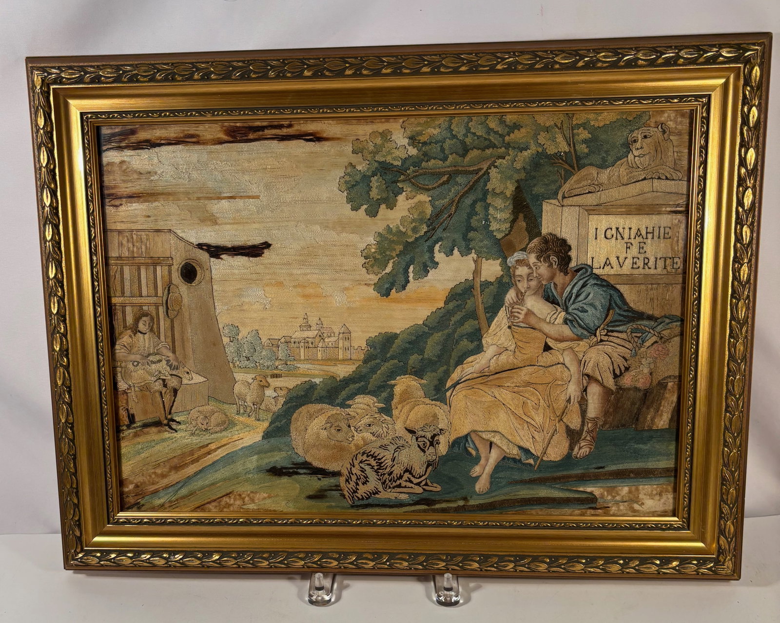 A European Silk Embroidery Allegorical Scene with Children and Lamb Monument: Decorative silk embroidered panel depicting two children writing beside a stone monument inscribed with French text referring to truth (“…LA VERITÉ”). A lamb resting atop the monument symbo