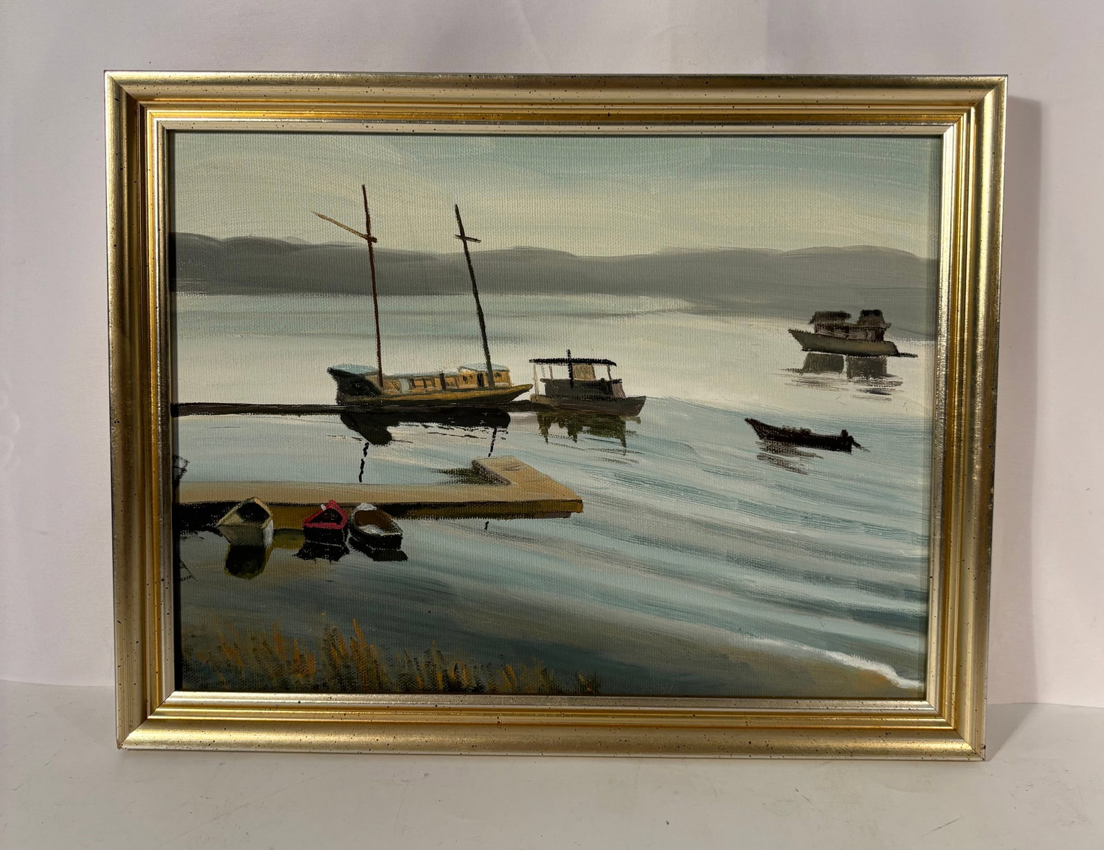 Contemporary Harbor Scene with Moored Boats: Unsigned contemporary oil on canvas depicting a tranquil harbor with sailboats, skiffs, and a distant shoreline under soft atmospheric light. The artist uses muted gray-blue tones and calm reflections