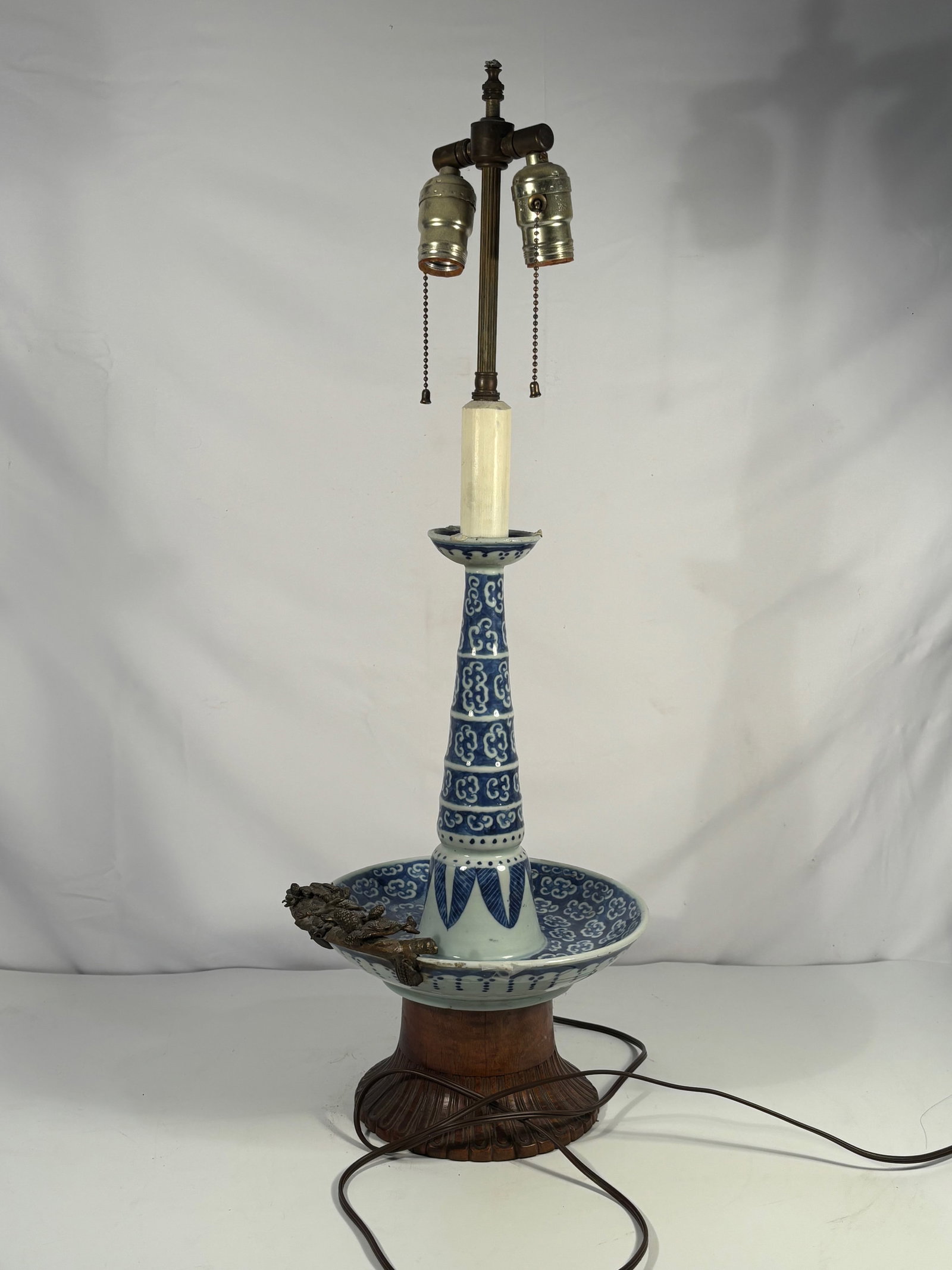 A Chinese Blue and White Porcelain Oil Lamp, Qing Dynasty, Later Adapted as Electric Lamp: Probably Early Qing dynasty(1644-1661),a tall slender-necked vase set into a wide dish-shaped reservoir, the neck painted with ruyi-head and cloud-scroll motifs, above a band of upright lappets, the d
