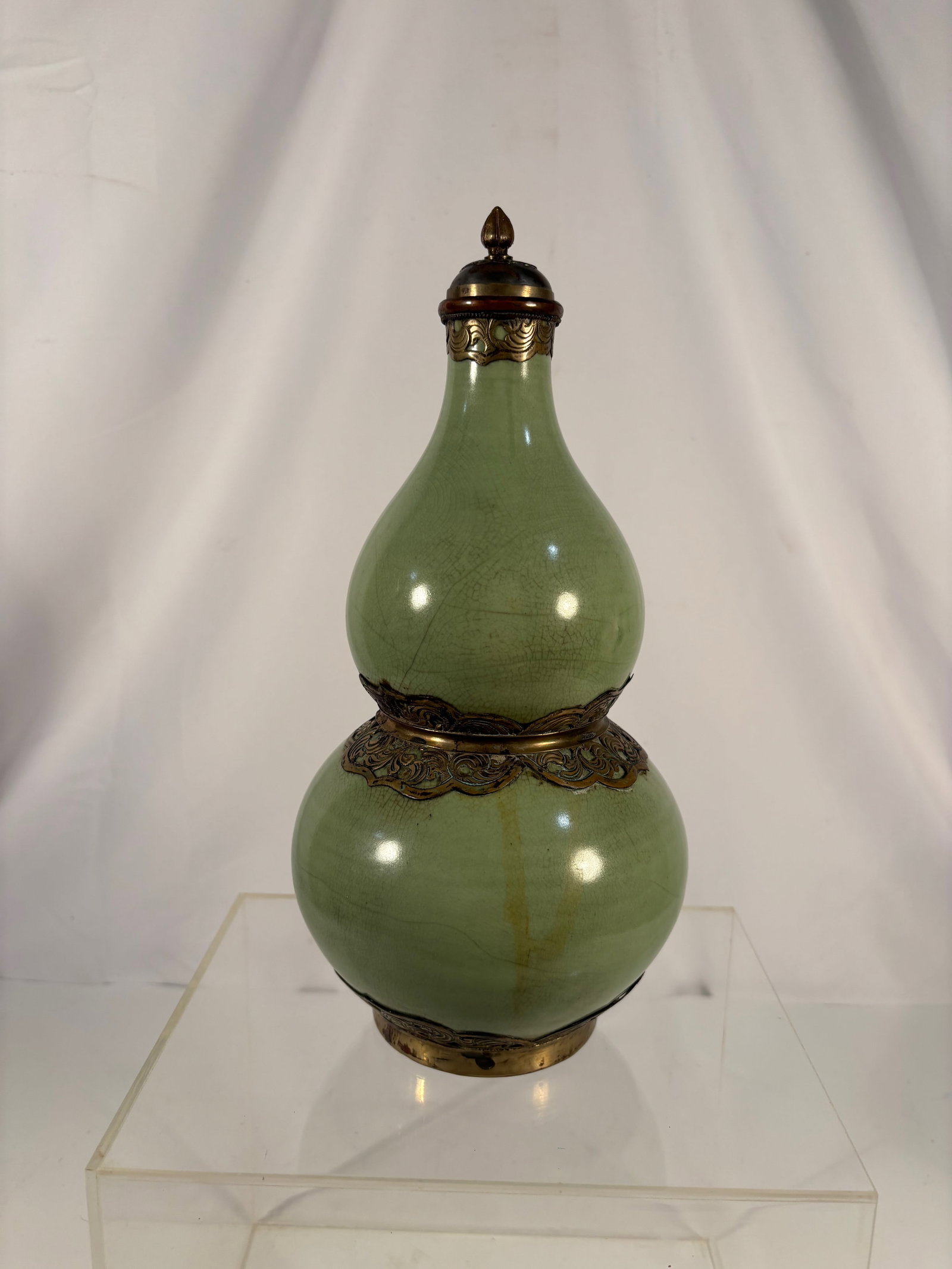 A Chinese Green Crackle-Glazed Double Gourd Vase with Metal Mounts: Likely late Qing dynasty to Republic period (19th–early 20th century); A Chinese double-gourd form vase with celadon green glaze, the surface with an extensive crackle network, mounted with gilt-met