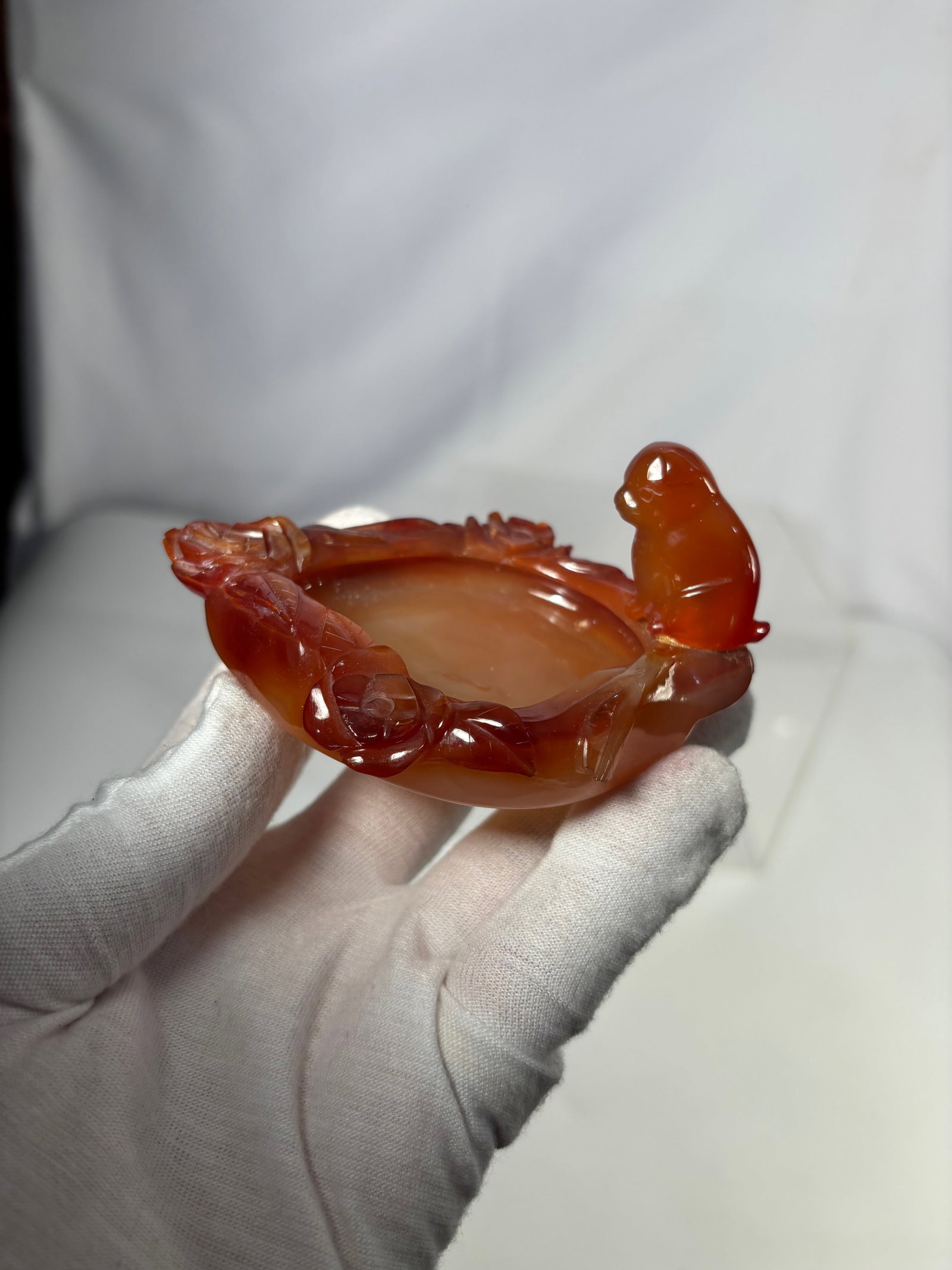 A Chinese Carved Red Agate Brush Washer with Monkey and Foliage Motif: Finely carved Chinese red agate brush washer of oval form, featuring a central shallow basin surrounded by sculpted foliate motifs and playful monkey figures in high relief. The stone displays attract