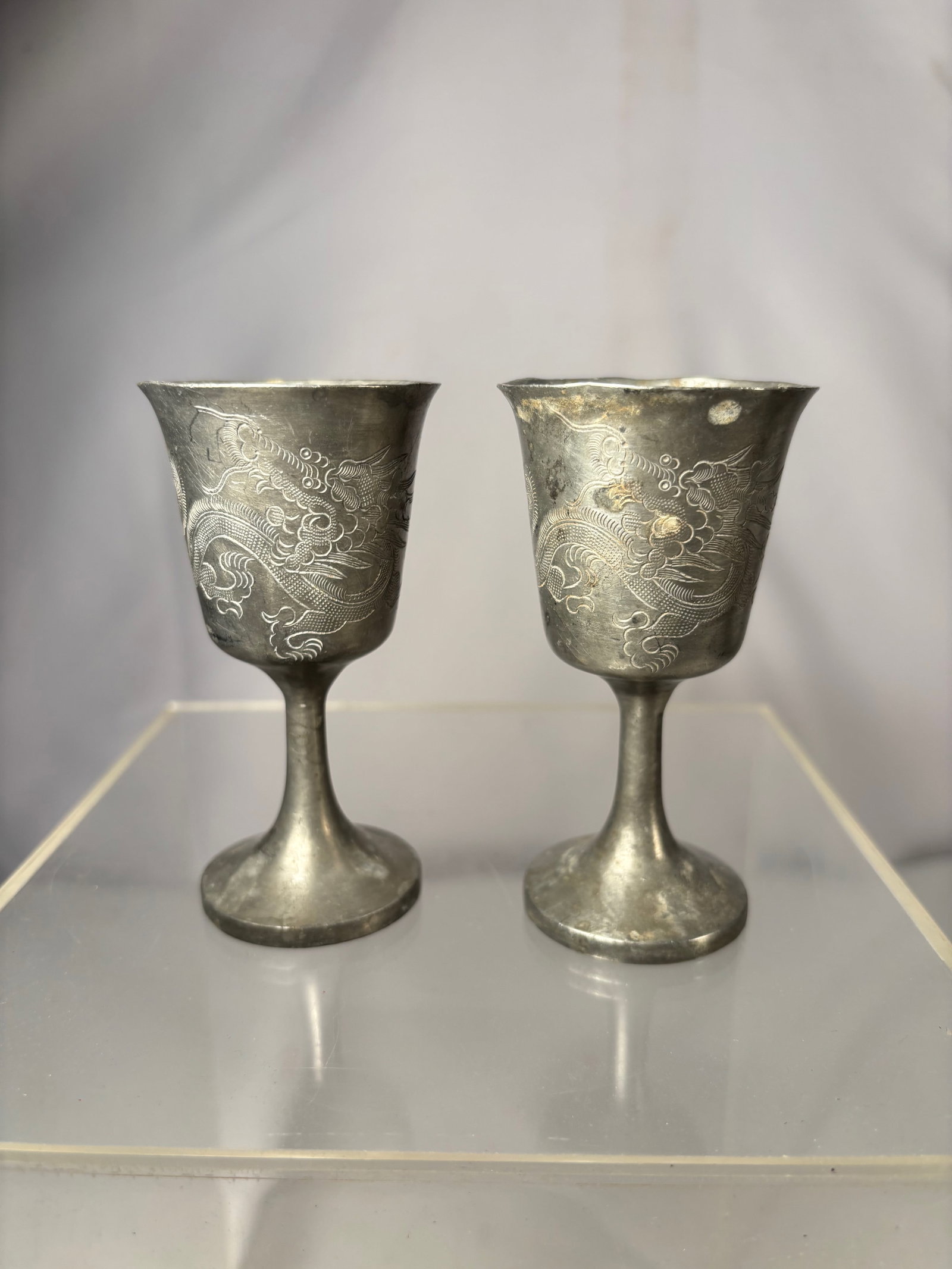 Pair of Vintage Engraved Pewter Goblets w/ Dragon Motif & “Baton?? Inscription: A matched pair of vintage pewter goblets, each decorated with an engraved dragon motif in a stylized East Asian manner. The bodies show hand-engraved detailing with a soft gray pewter patina throughou