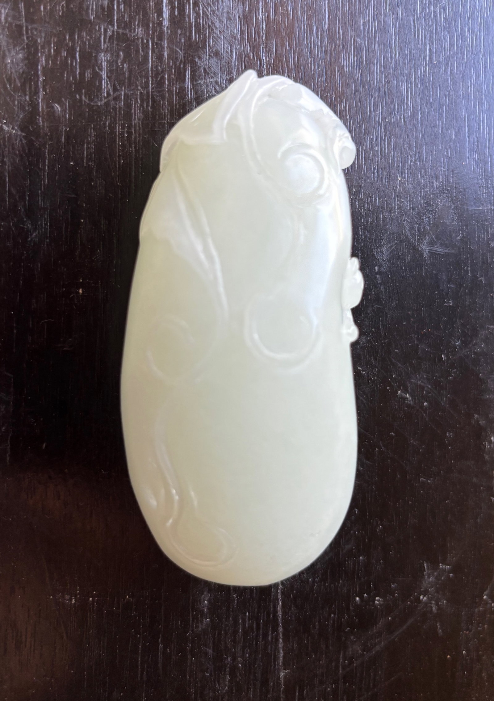 A Chinese White Jade Peapod/ Gourd toggle: Qing Dynasty (1644-1912) or later, A heavy Chinese white jade pendant carved in the form of a stylized peapod/ gourd with am animal clinging to its upper section.The jade is of translucent, pale white