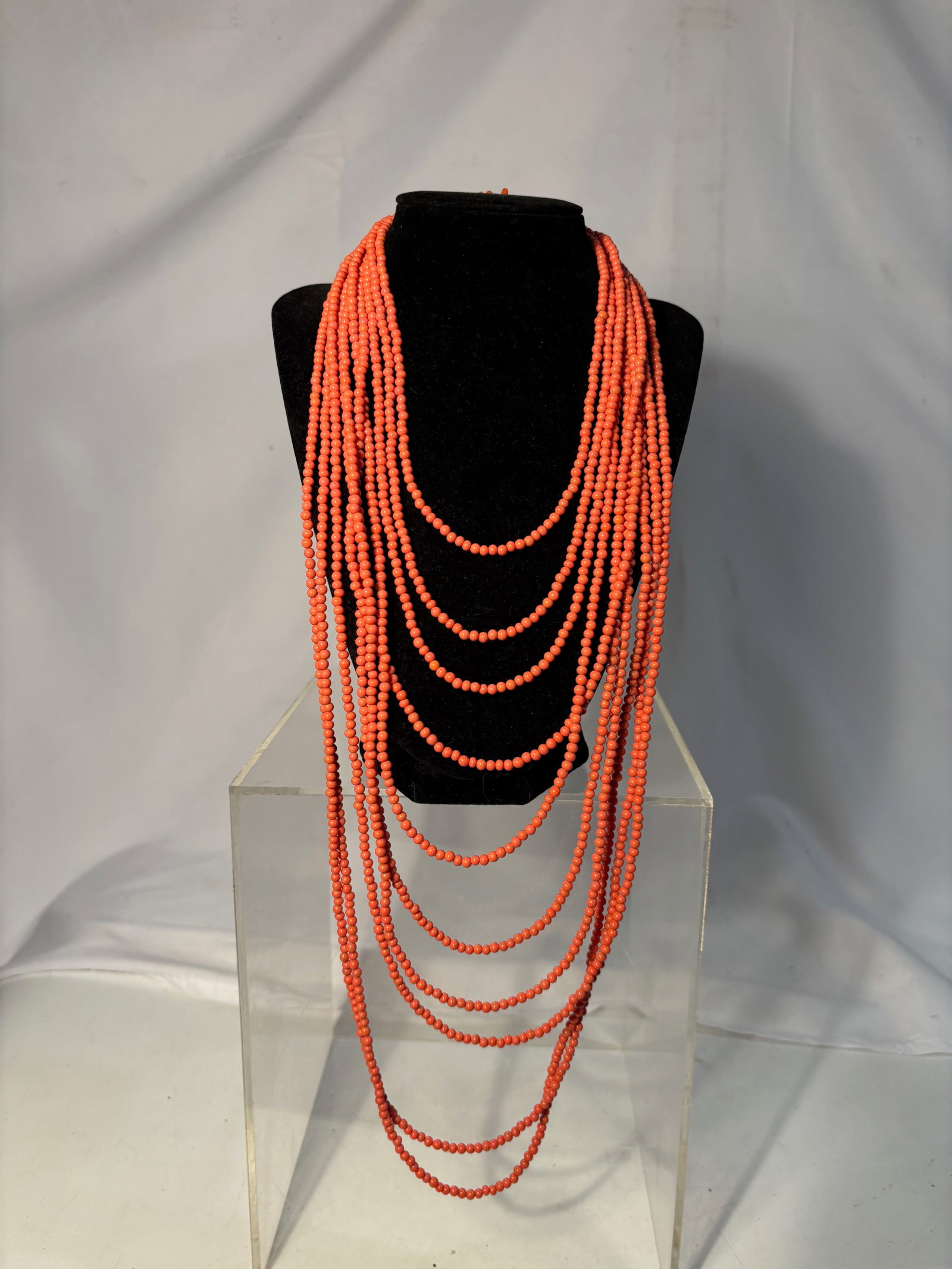 A Vintage 10-Strand Coral Style Beaded Necklace with Floral Clasp: Statement necklace composed of ten cascading strands of small orange-red beads, creating a dramatic layered effect. The piece is finished with an ornate floral centerpiece clasp, featuring coral-like 