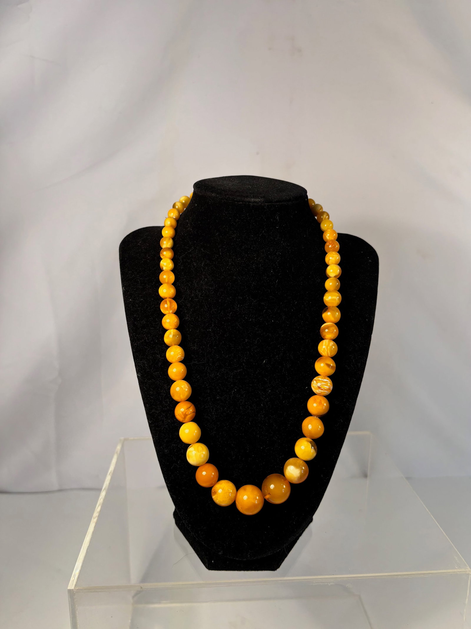 A Graduated Baltic Butterscotch Amber Bead Necklace, 20 inches, 32g: A finely graduated necklace composed of natural Baltic butterscotch amber beads, hand-carved and polished to a soft gloss.The spherical beads display rich yellow to honey-orange tones with natural mar