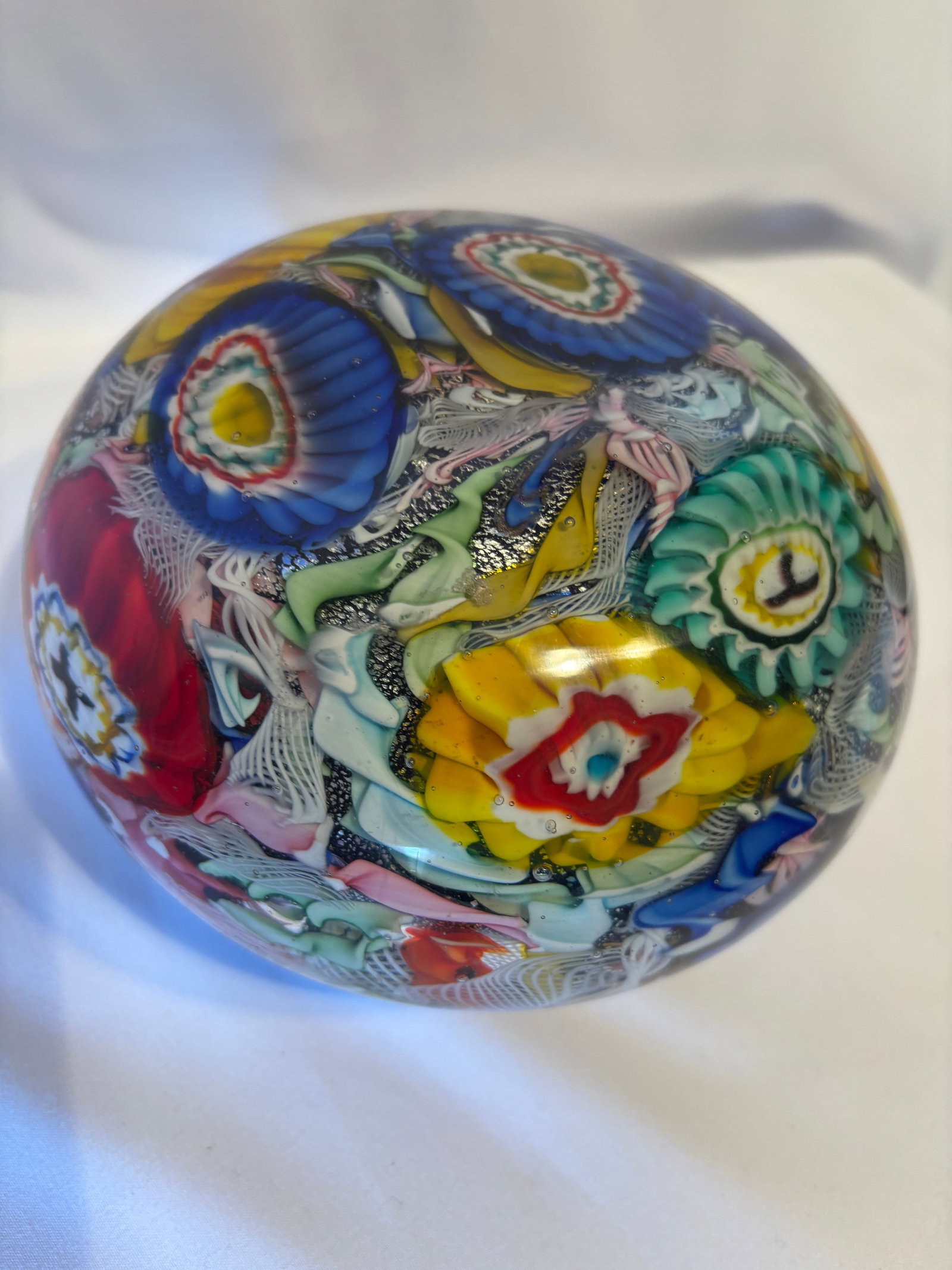 Large Murano Art Glass Millefiori Paperweight: Large Murano style art glass paperweight or orb, of domed form with intricate millefiori canes, latticinio filigree, floral motifs, and multicolored abstract inclusions. The composition features vibra