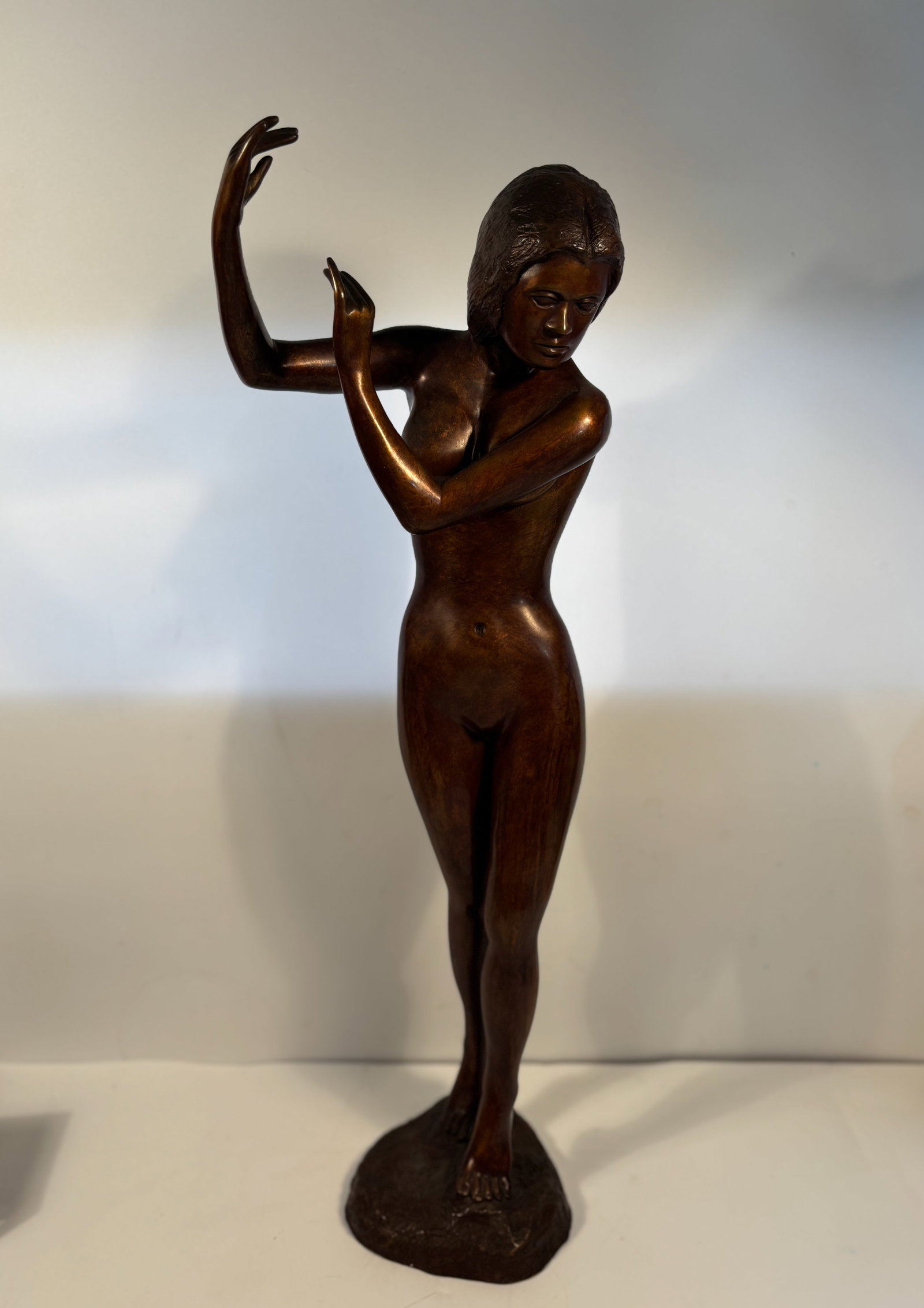 A Large Bronze Sculpture of a Dancing Nude Female, Signed and Dated 1975: Modernist or mid-century-inspired figure, with stylized hair and pose, reminiscent of dance or performance themes. Cast bronze with smooth patina. Dimensions?Height: 26 inches; Width: 9 inches.