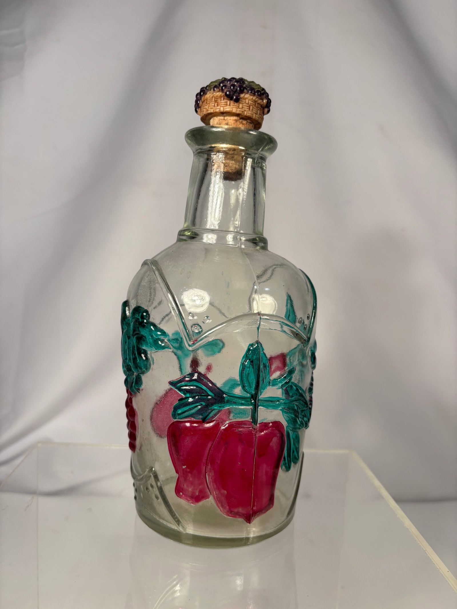 Vintage Painted Glass Cruet/Decanter Bottle with Fruit Motif: A clear glass bottle of paneled form with a cork stopper (barrel-shaped cork top). Hand-painted in cold-paint enamel with a fruit and foliage design — apples in deep red, clusters of cherries or cur