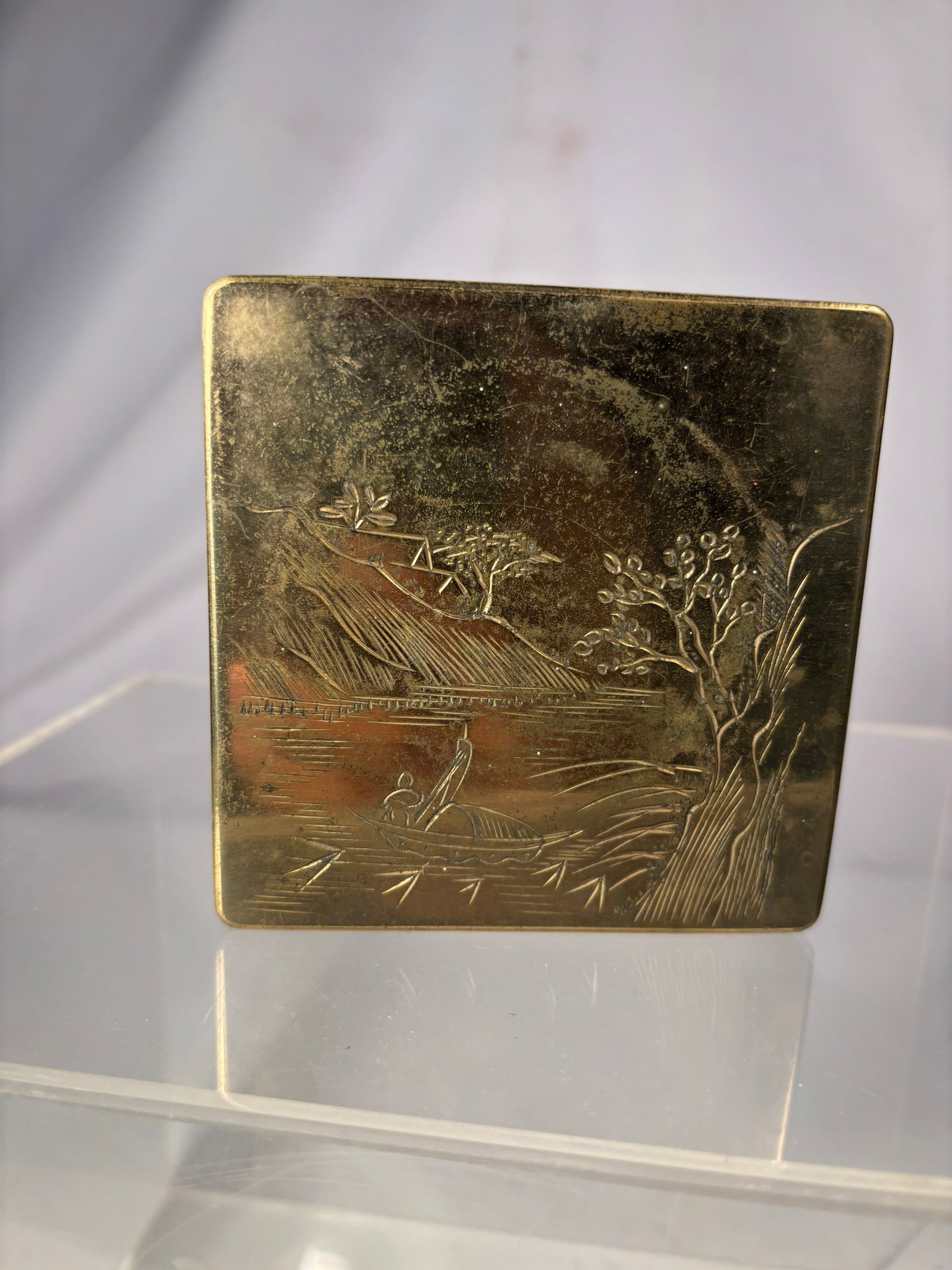 Chinese Engraved Bronze Ink Box 19th century: A Chinese Square bronze ink box with a fitted lid, finely engraved with a traditional landscape depicting a fisherman in a boat, trees, mountains and distant pavilions. Traditionally used by scholars 