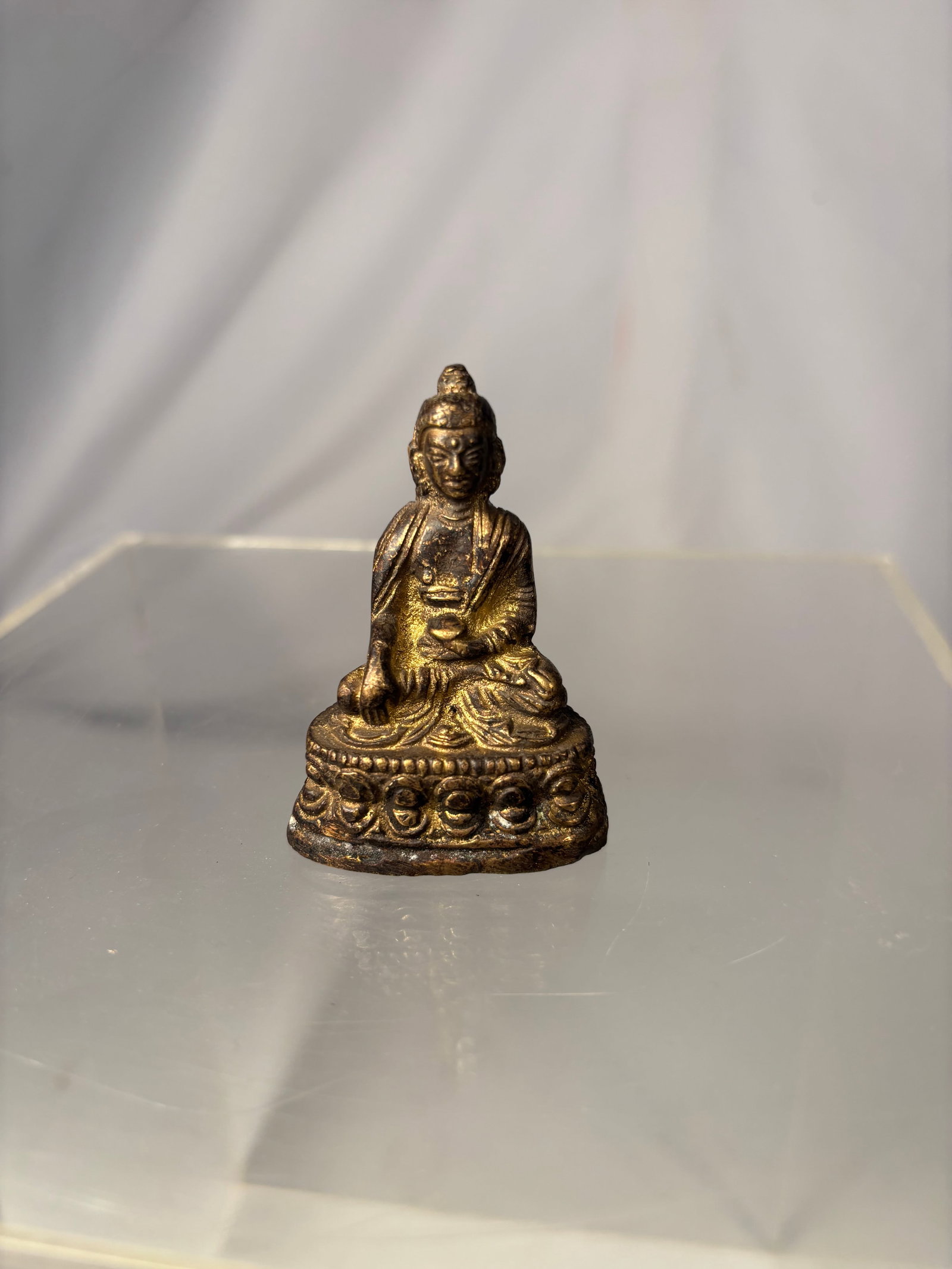 Tibetan Gilt-Bronze Figure of Shakyamuni Buddha 19th century: A 19th-century Tibetan gilt-bronze figure of the crowned Shakyamuni Buddha, seated in dhyanasana upon a double-lotus pedestal. His right hand performs the earth-touching bhumisparsha mudra, while his 
