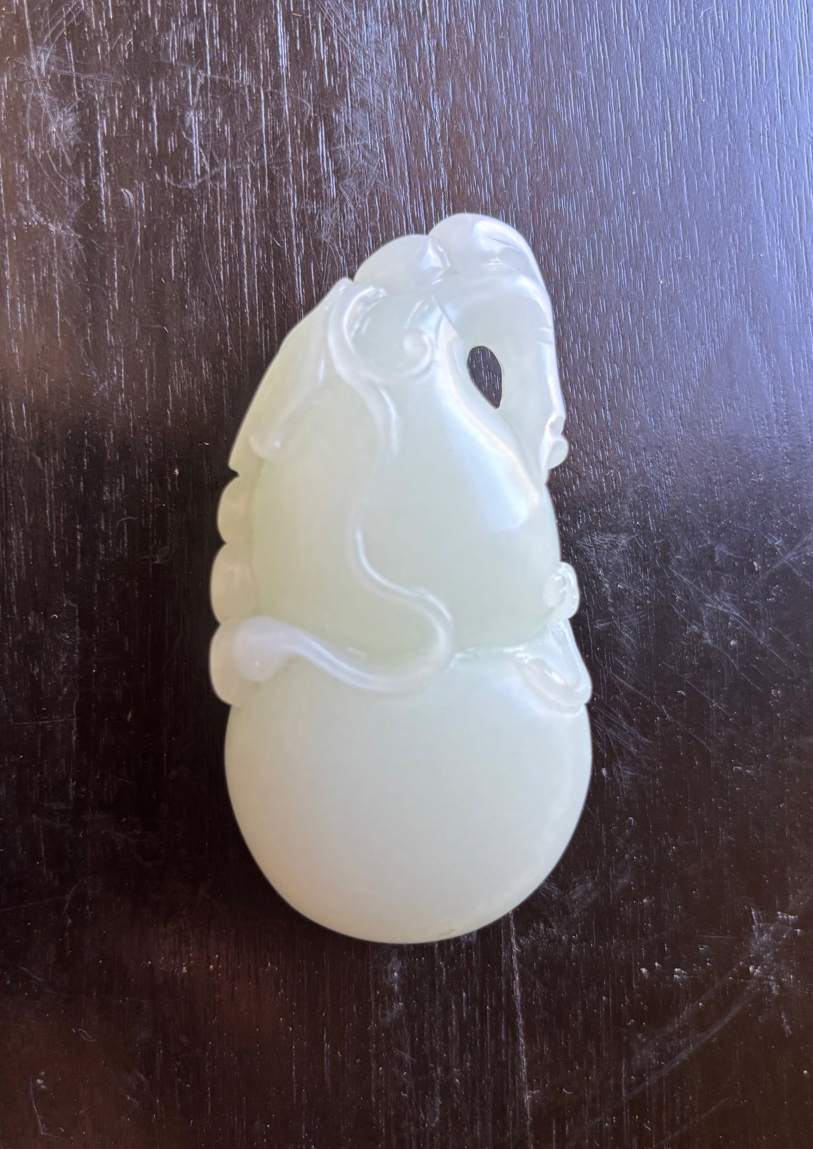 A Chinese White Jade Carving of a Monkey Climbing a Gourd: Qing Dynasty (1644-1912) or later; A finely carved white jade figure depicting a monkey climbing atop a double gourd. The jade is of a soft, milky white tone with areas of natural translucency and
