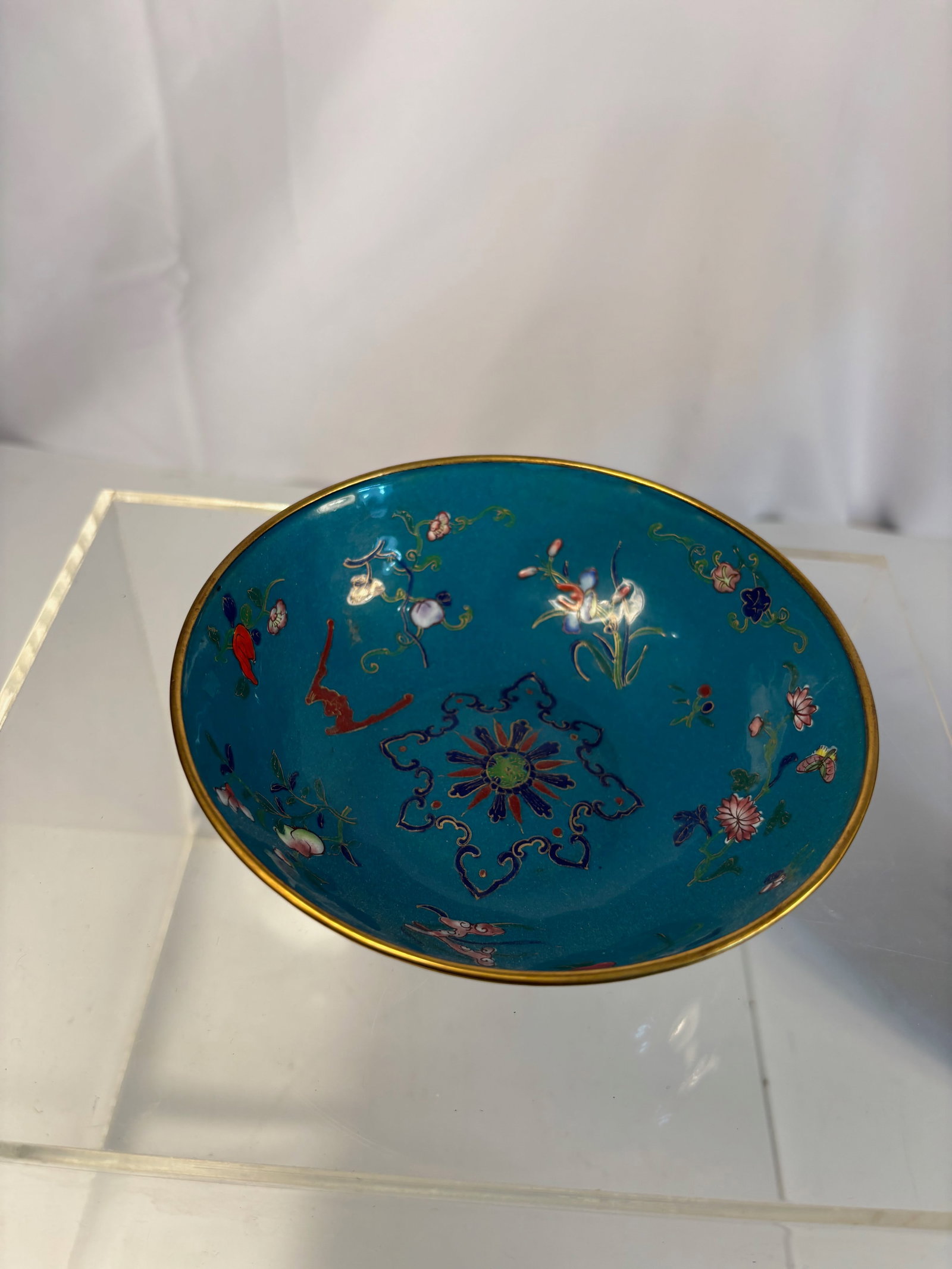 A Chinese Cloisonné Enamel Bowl with Floral Design: Qing dyansty(1644-1912) ; An antique Chinese cloisonné enamel bowl decorated with multicolored floral and foliate scrolls on a rich turquoise ground. The exterior and interior are both crafted using 