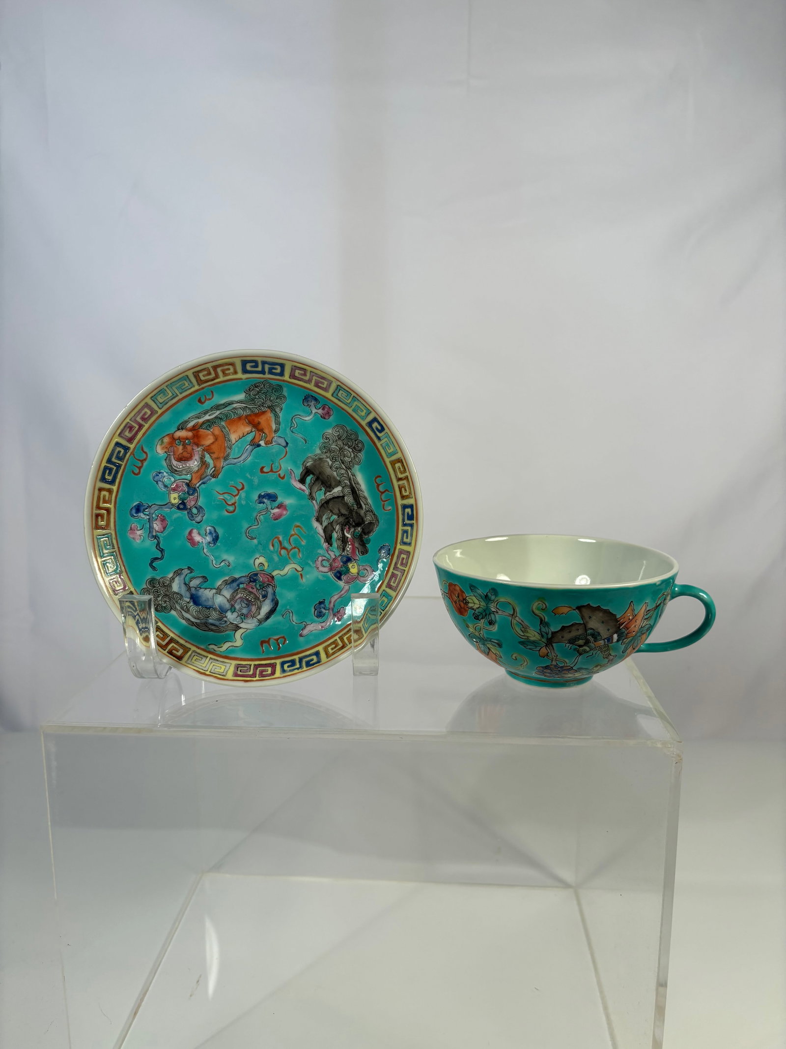 Chinese Famille Turquoise Porcelain Tea Cup and Saucer: Qing Dynasty(1644-1912); A finely enameled Chinese porcelain tea cup and saucer with turquoise ground, decorated with fu lions and floral scrolls, bordered by polychrome key-fret design. Dimensions? P