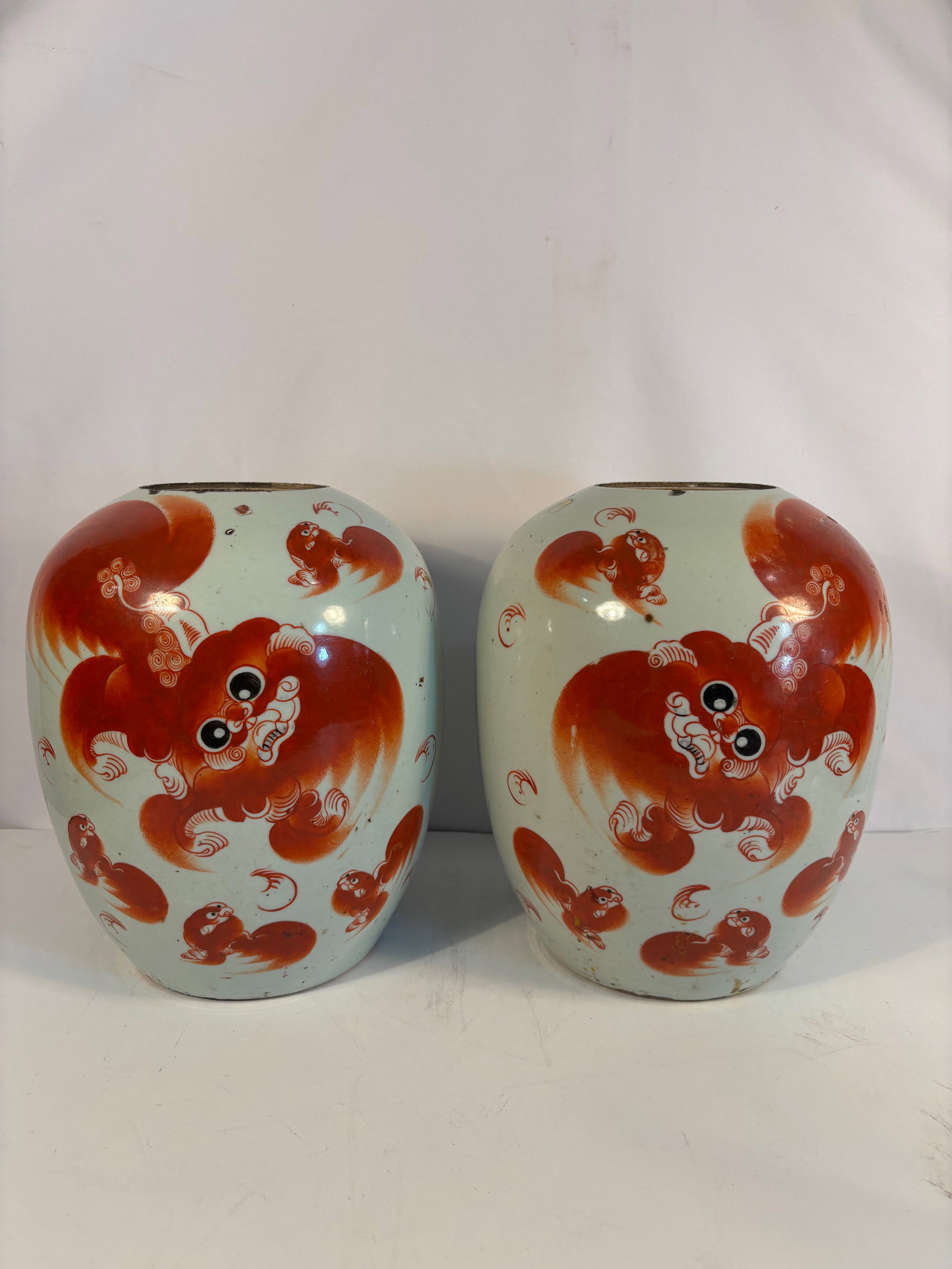Pair of Chinese Porcelain Jars with Iron-Red Buddhist Lions: Qing dyansty(1644-1912) ; A pair of Chinese porcelain jars finely decorated in iron-red enamel with lively Buddhist lions frolicking among swirling ribbons and brocade balls. The rounded bodies are se