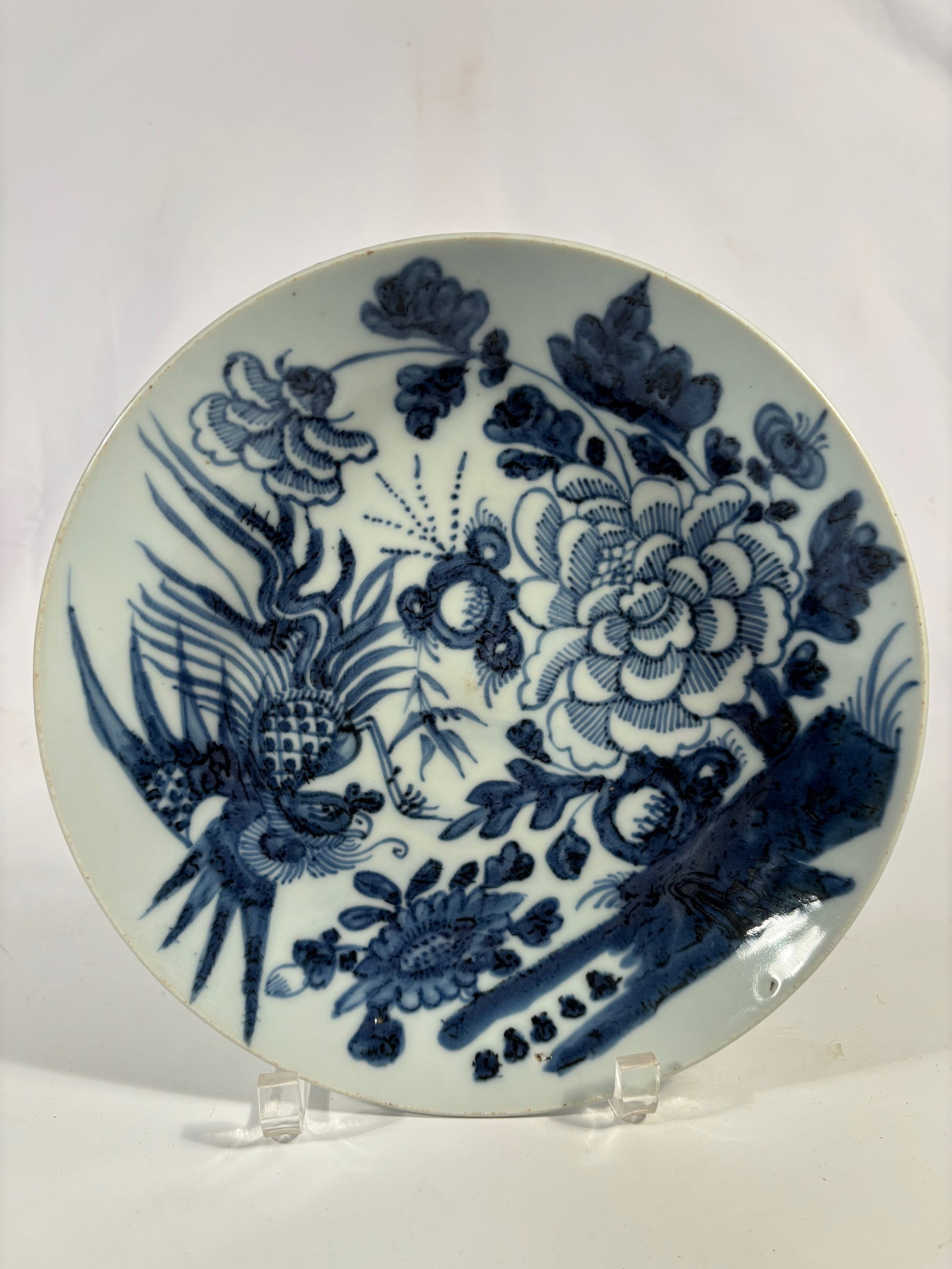 A Chinese Blue and White Porcelain Plate with Pheonix and Peony Design: Qing dynasty(1644-1912);Finely potted porcelain plate decorated in underglaze blue with a bird perched among blossoming peonies and bamboo, the design framed by scrolling foliage and a single butterfl