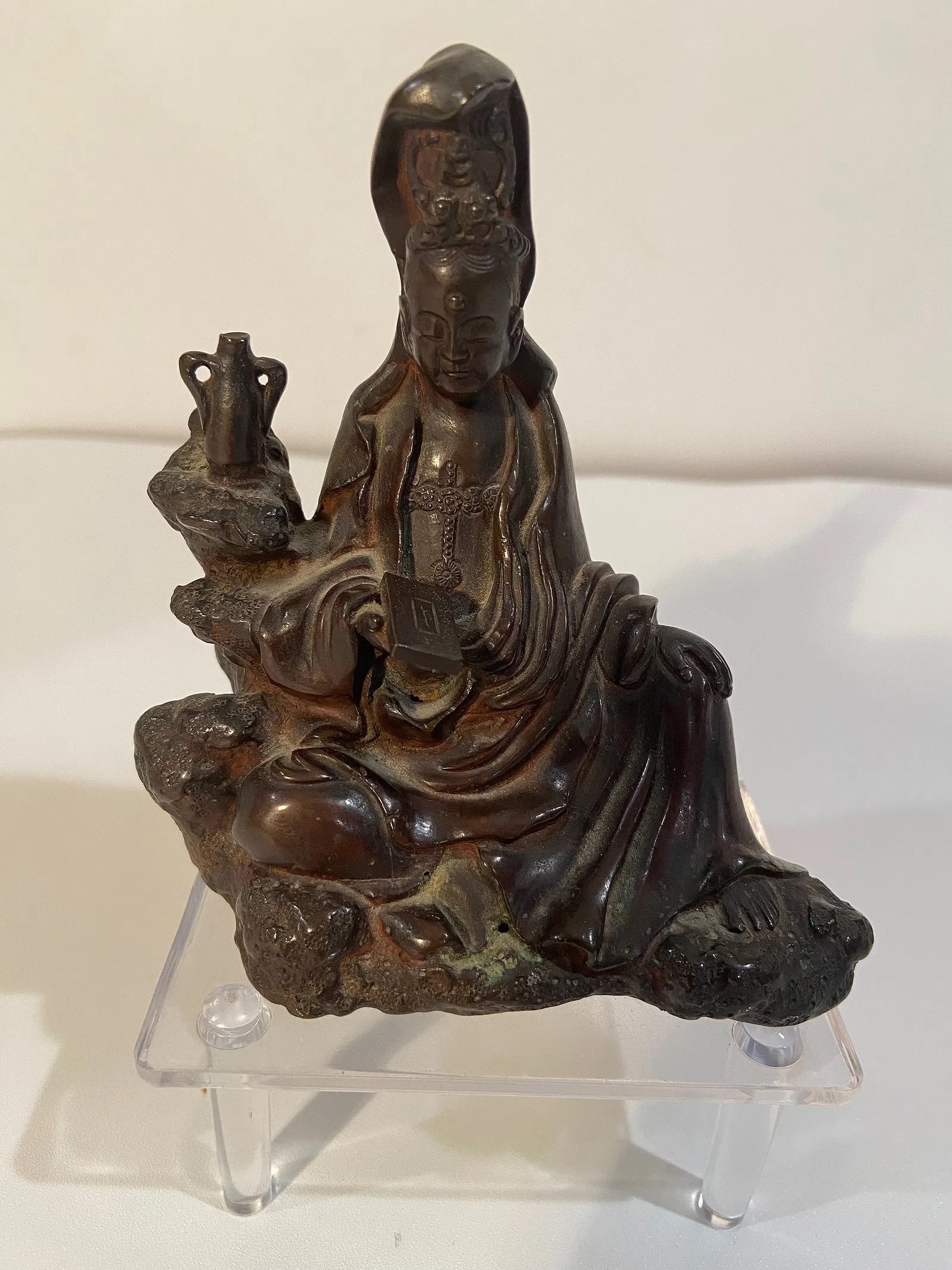 An Asian bronze Guanyin statue: 19th Century; The figure is seated on a naturalistic rocky base. The flowing robes and detailed adornments are typical of Guanyin or Buddhist figures. Dimensions?Height: 4 inches
