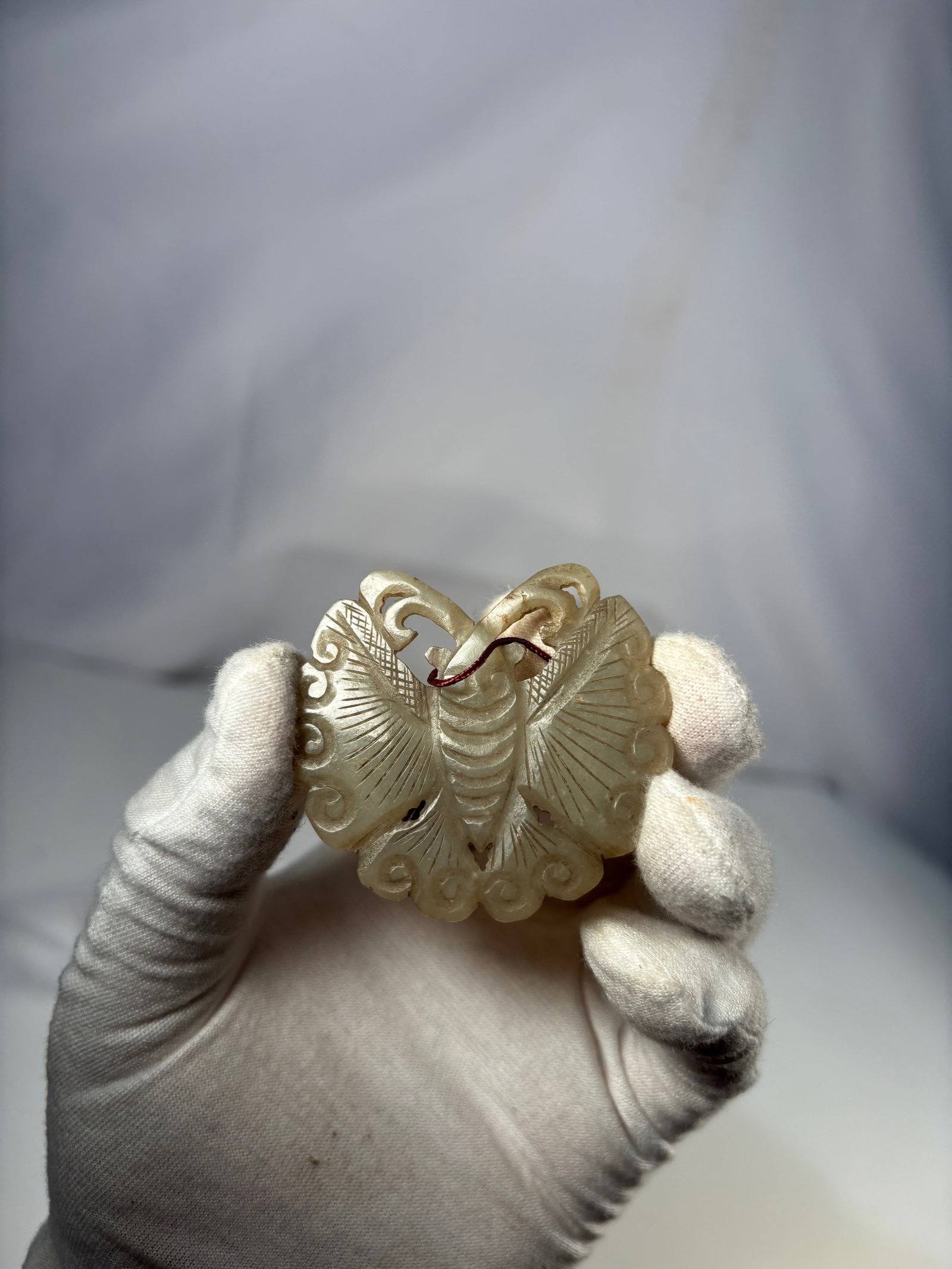 A Chinese Carved Jade Butterfly Pendant: Qing dynasty(1644-1912); Chinese carved jade pendant depicting a stylized butterfly with outspread wings, finely rendered with openwork carving and incised linear details. The stone is a pale celadon 