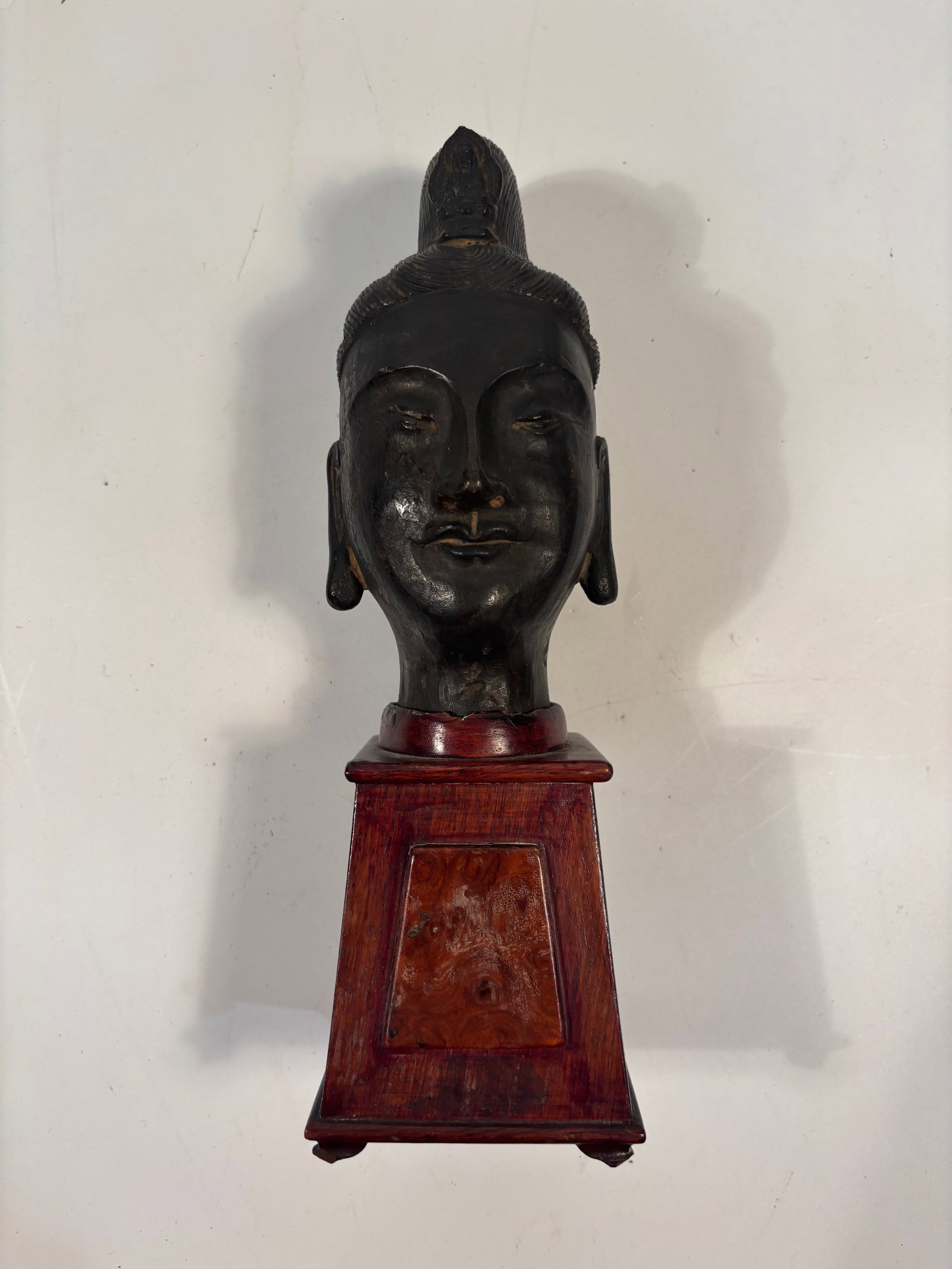 A sculptural bronze Buddha head with wood base: 19th Century or early ; HEIGHT: 11.5 INCHES including wood base
