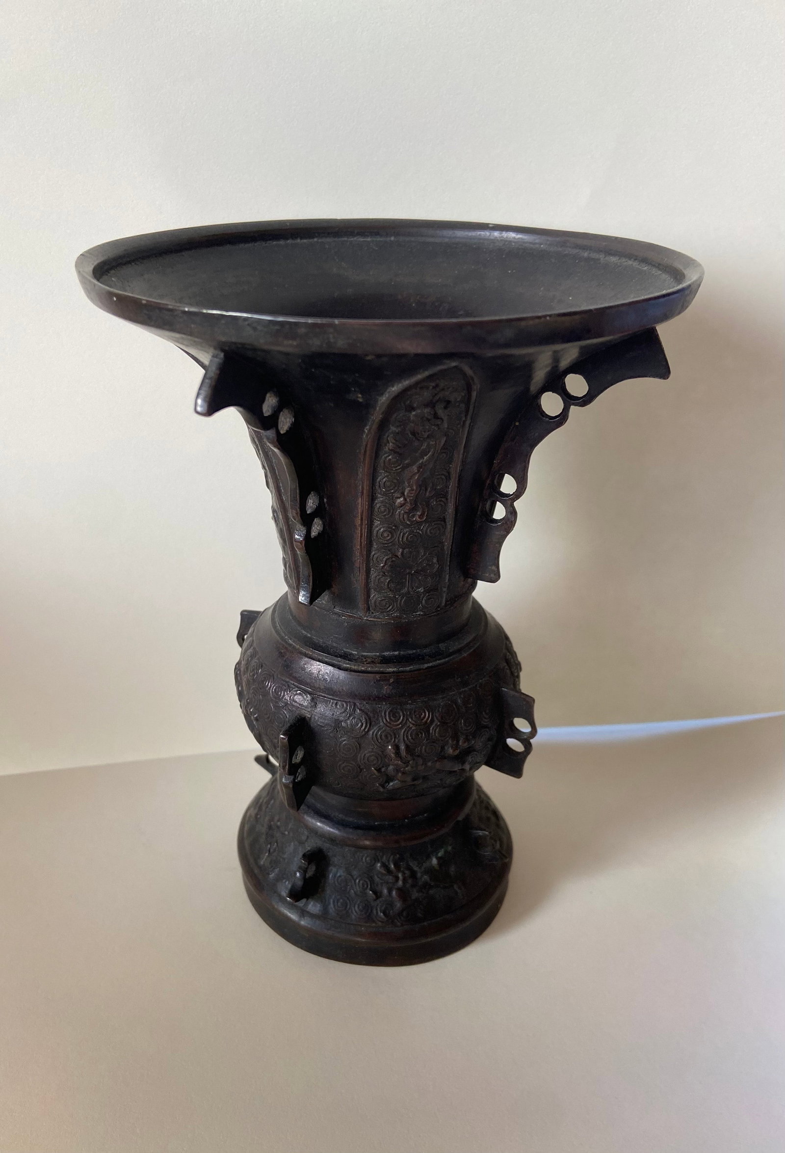 A Chinese Bronze vase: Qing Dynasty (1644-1912) ; Taotie mask motifs and spirals:Sectioned panels with raised relief: Dimensions?Height: 7 inches; Diameter: 5.25 inches.